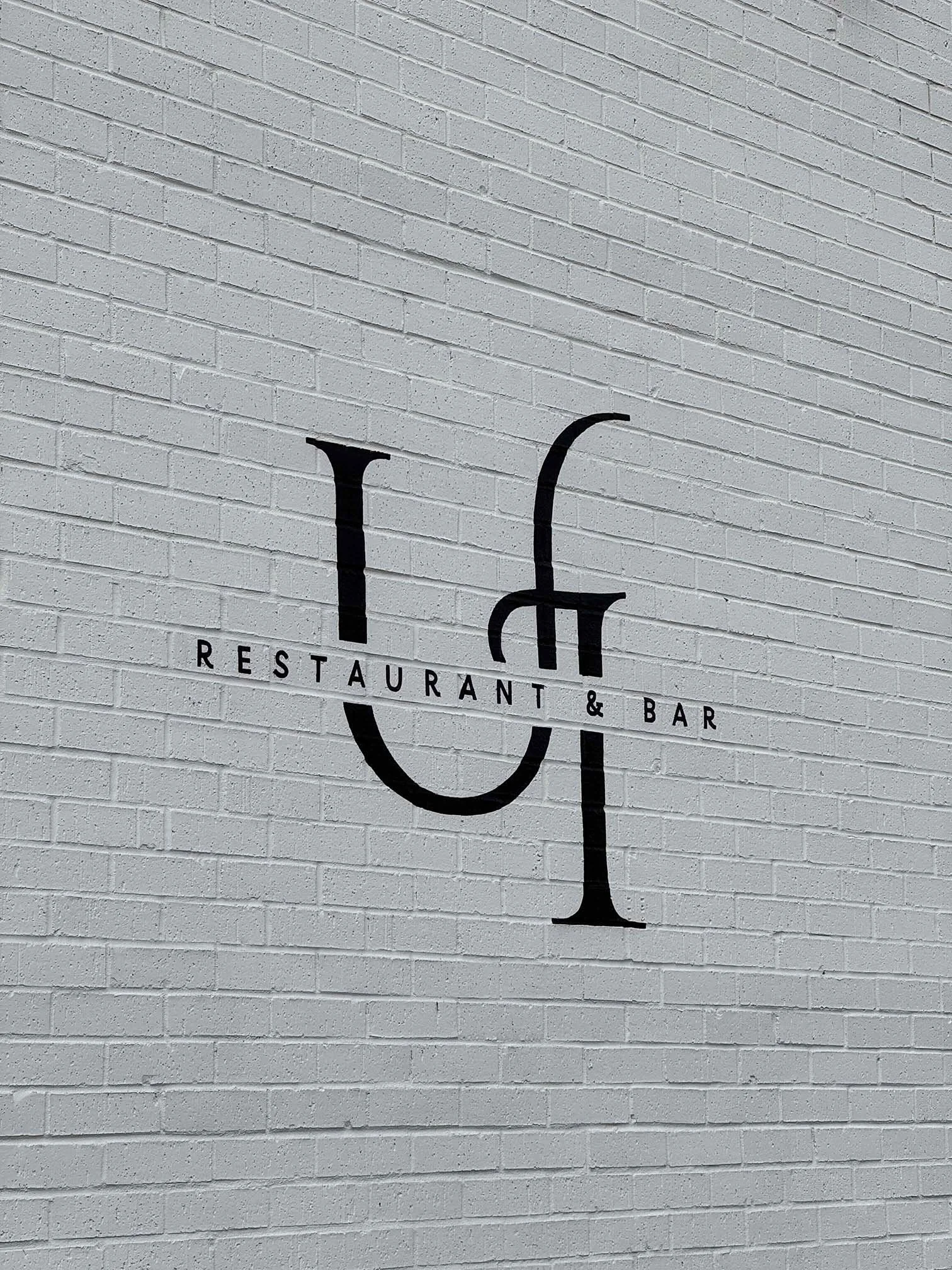 U&I Restaurant and Bar logo displayed on a white painted brick wall in Murfreesboro, Middle Tennessee.