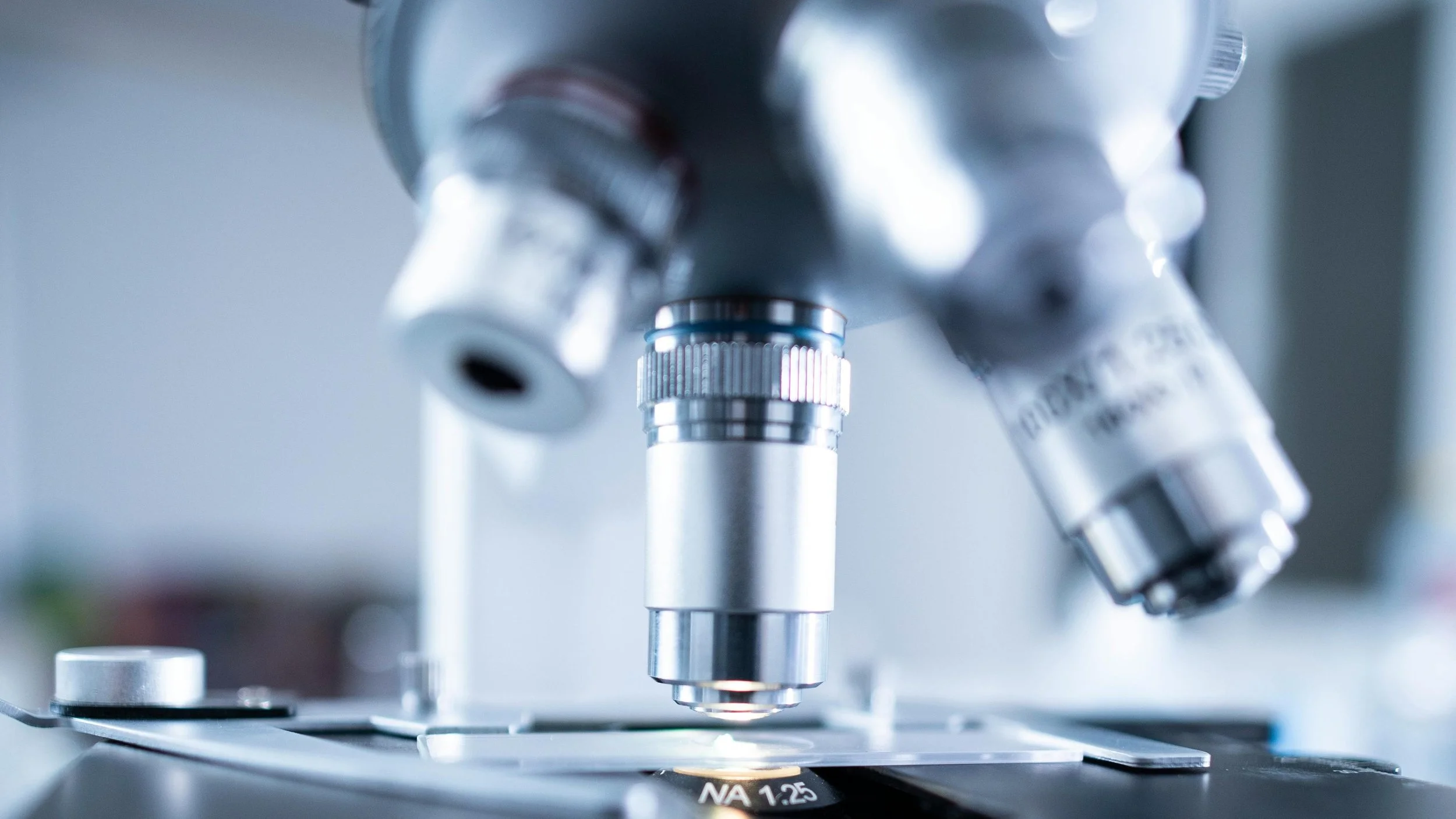 Close-up of a microscope focusing on a specimen slide in a laboratory setting.