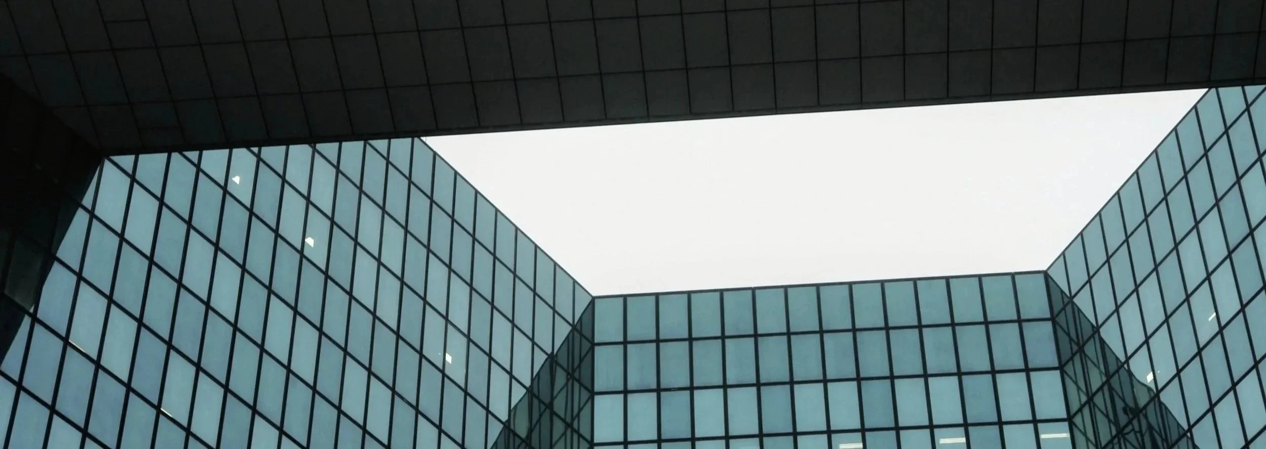 Looking up at a modern glass office building with a central open sky courtyard.