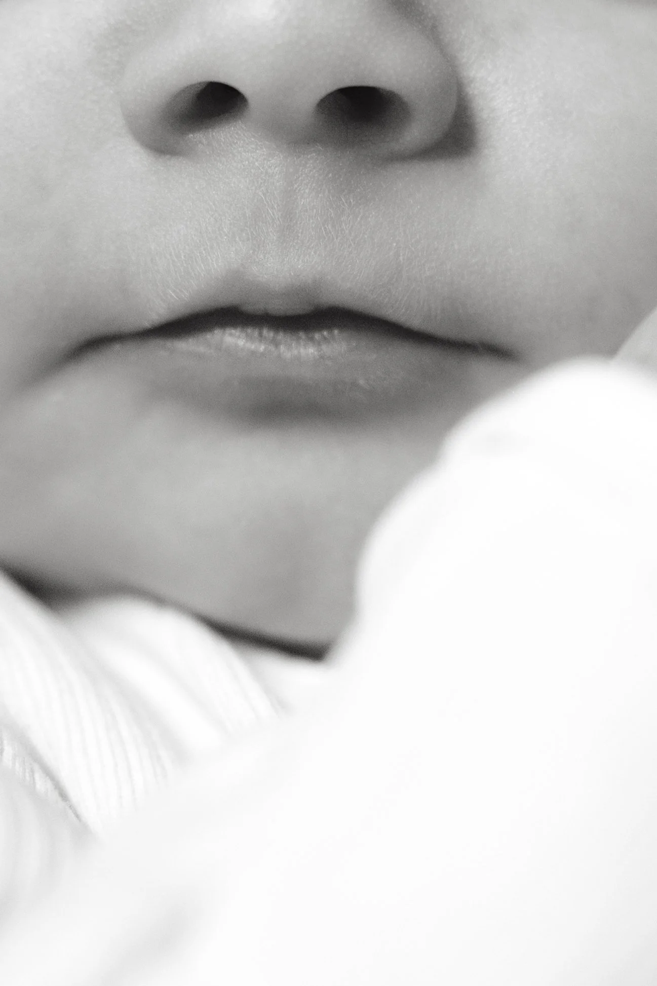 Close-up black and white photograph of a person's nose and lips.