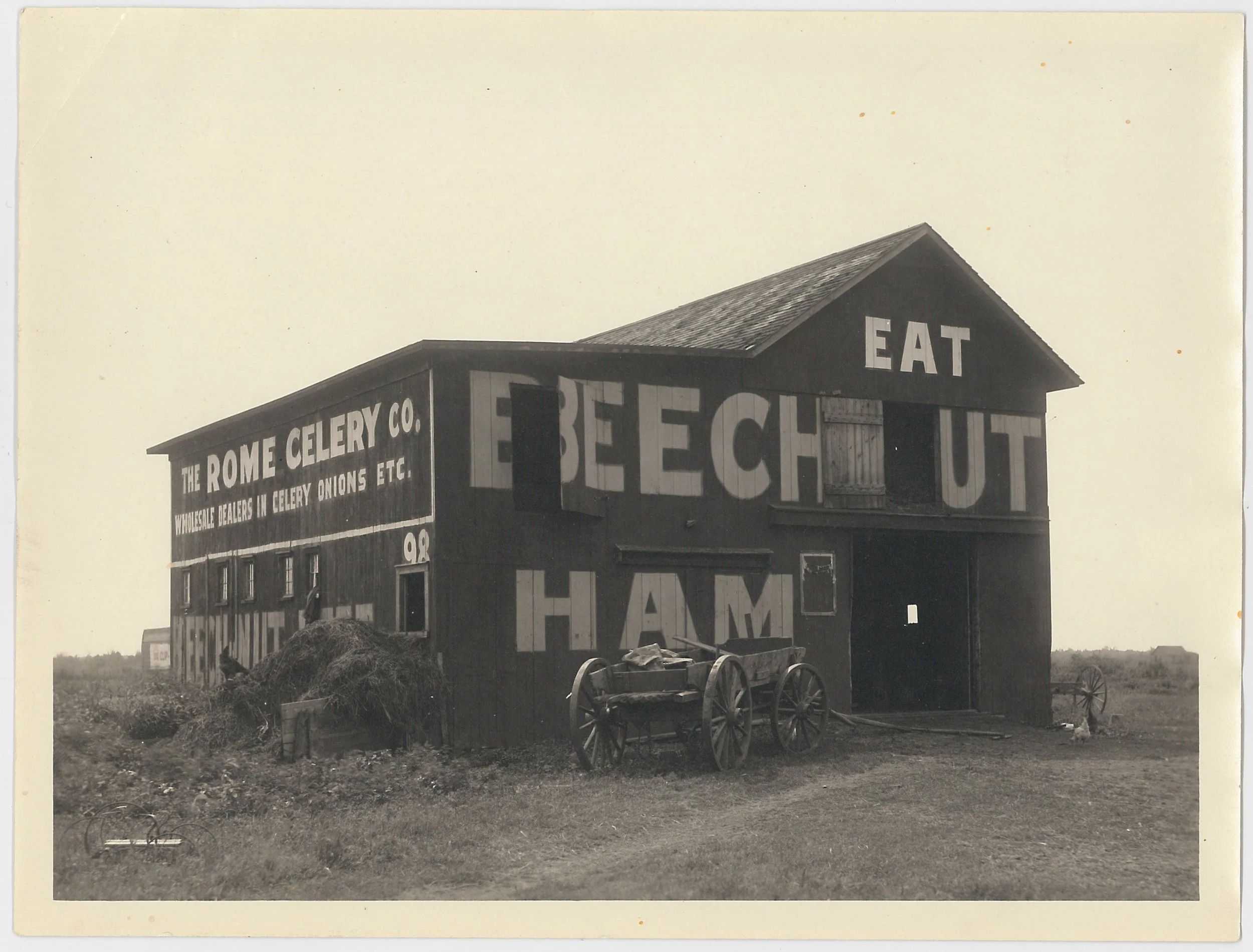 Black and white photo of a barn with Beech-Nut advertisements on it. There is a wagon out front.