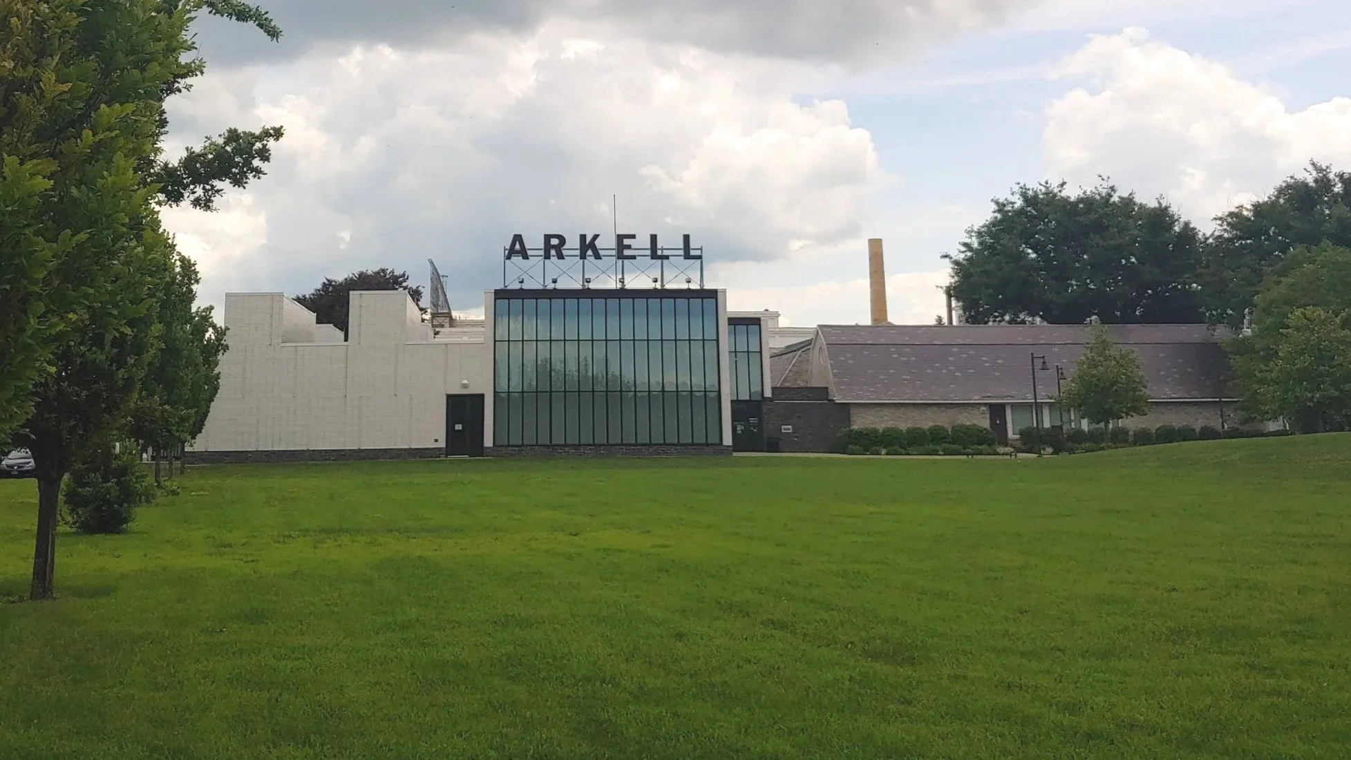 Picture of a large white building with vertical windows and a sign on the roof that says Arkell