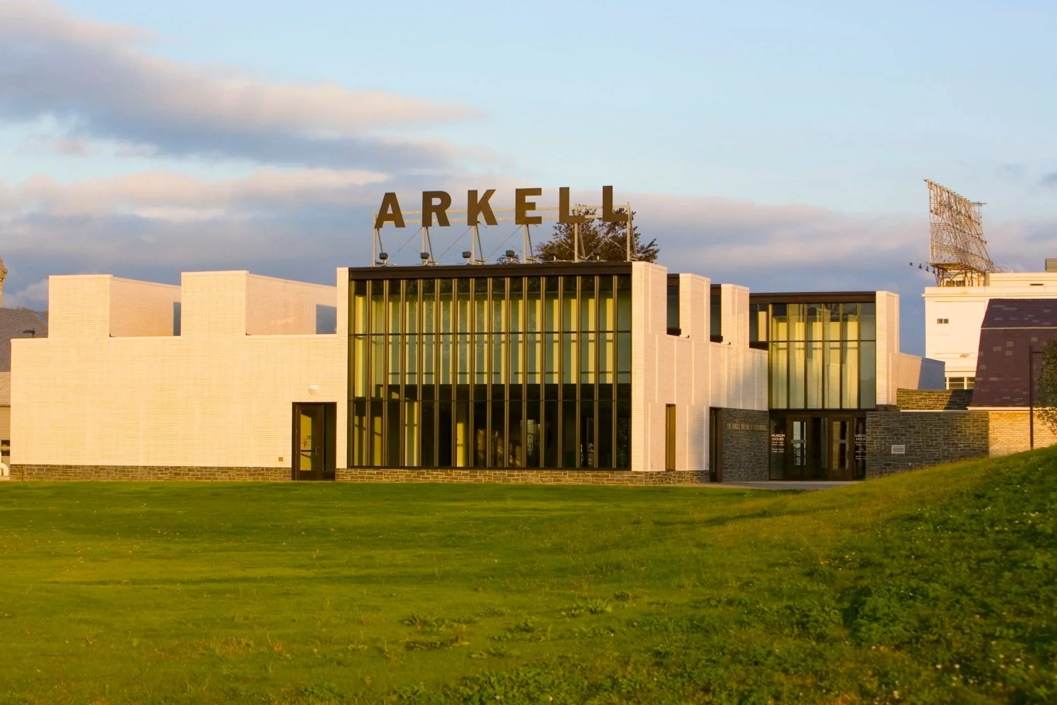 Picture of a large white building with vertical windows and a sign on the roof that says Arkell