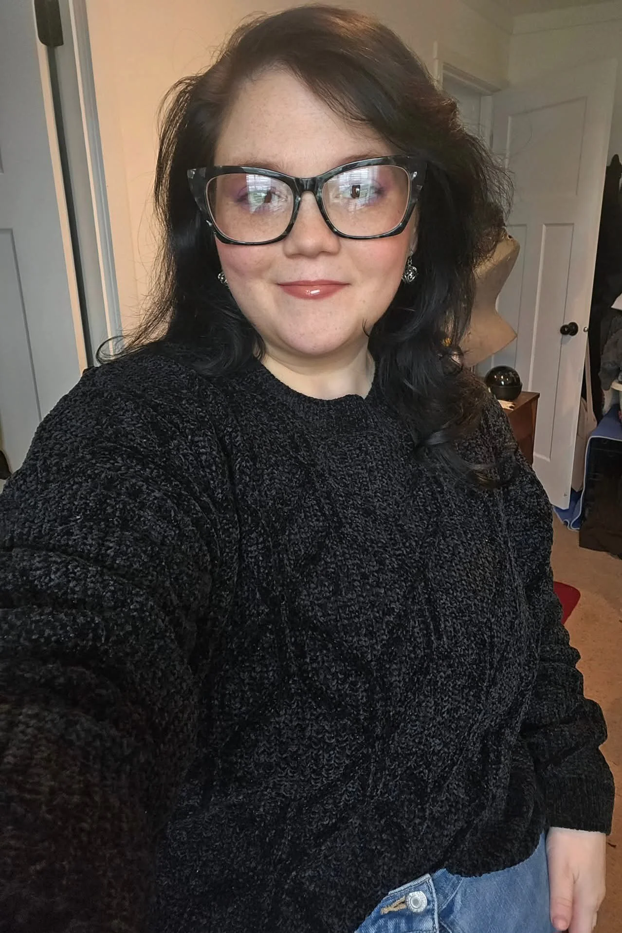 Picture of a woman in a black long sleeved shirt. She has dark black hair and wears glasses