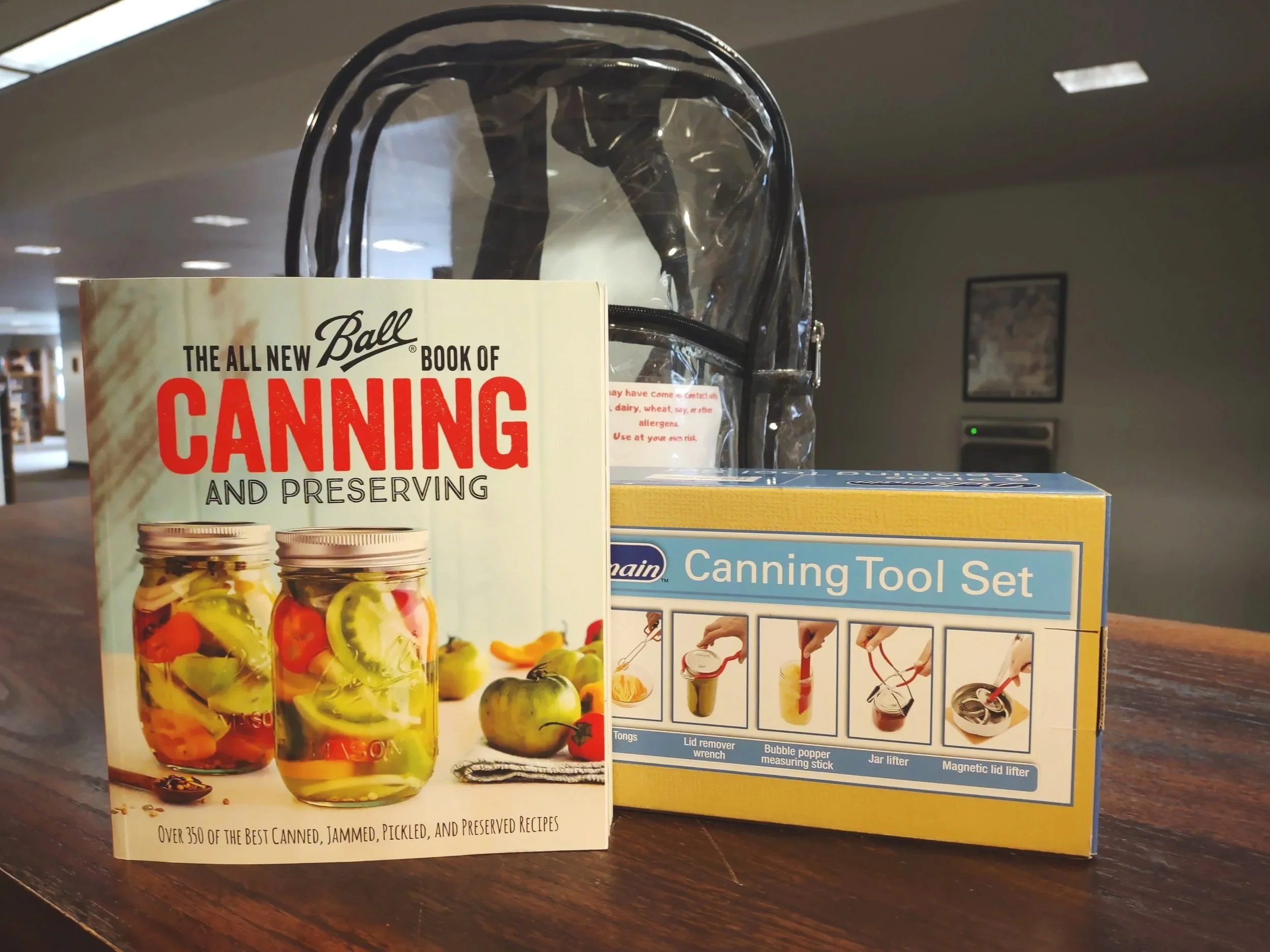 This is an image of a canning tool set and a copy of the all new ball book of canning and preserving