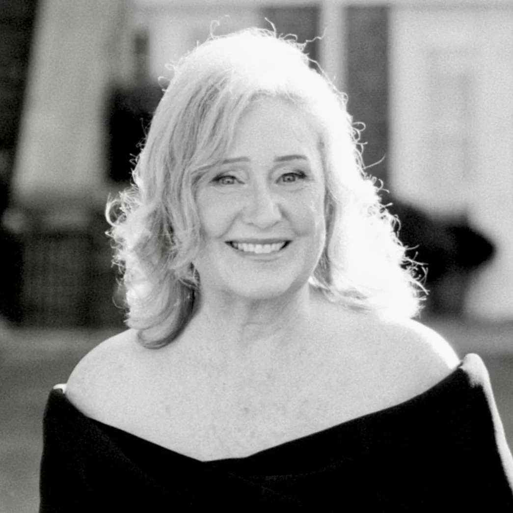 This is a black and white photo of trustee Debby Limoncelli. She is wearing a black dress and smiling widely.