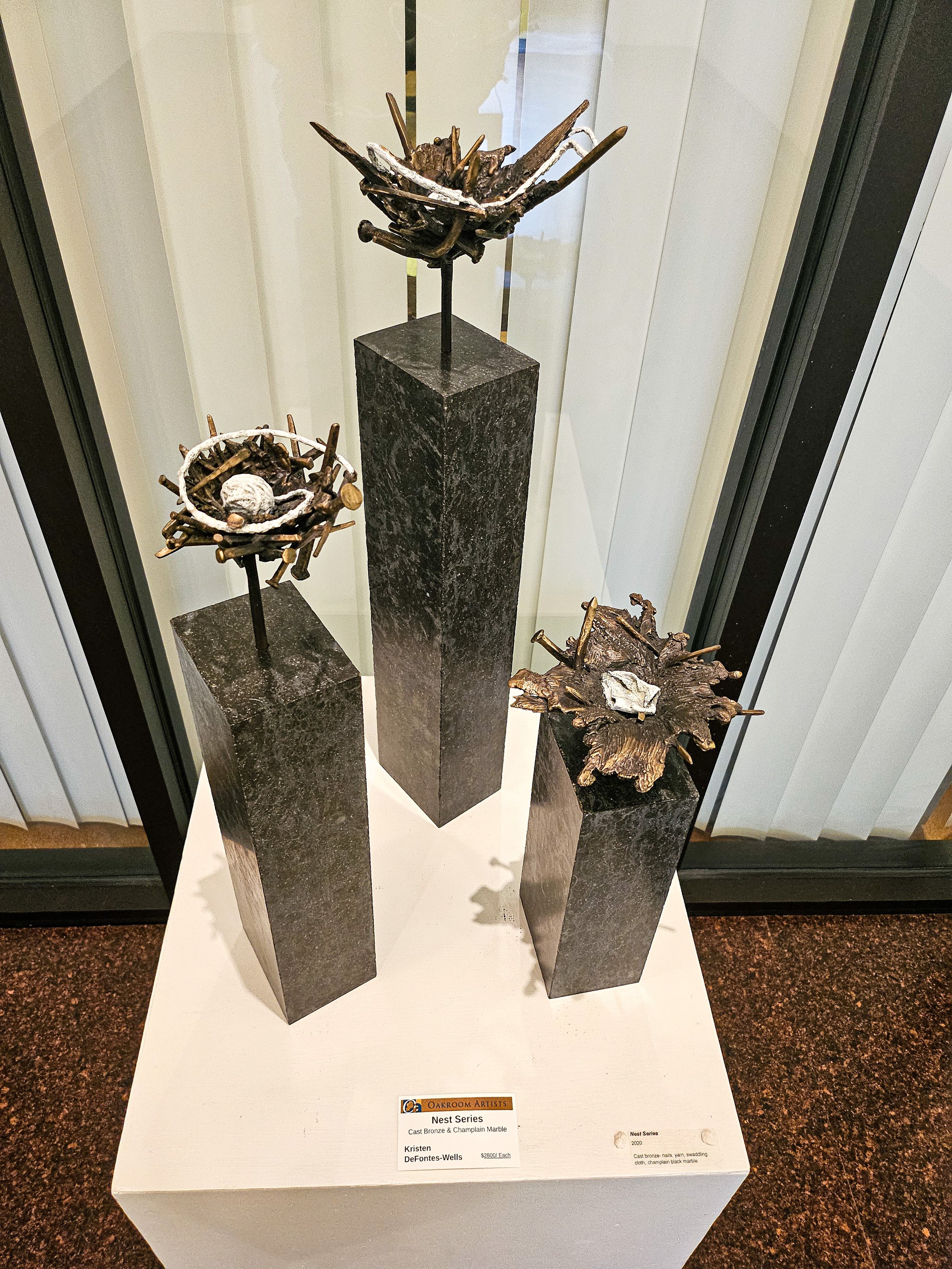 Three bronze cast sculptures resembling nests on pedastals of Champlain marble