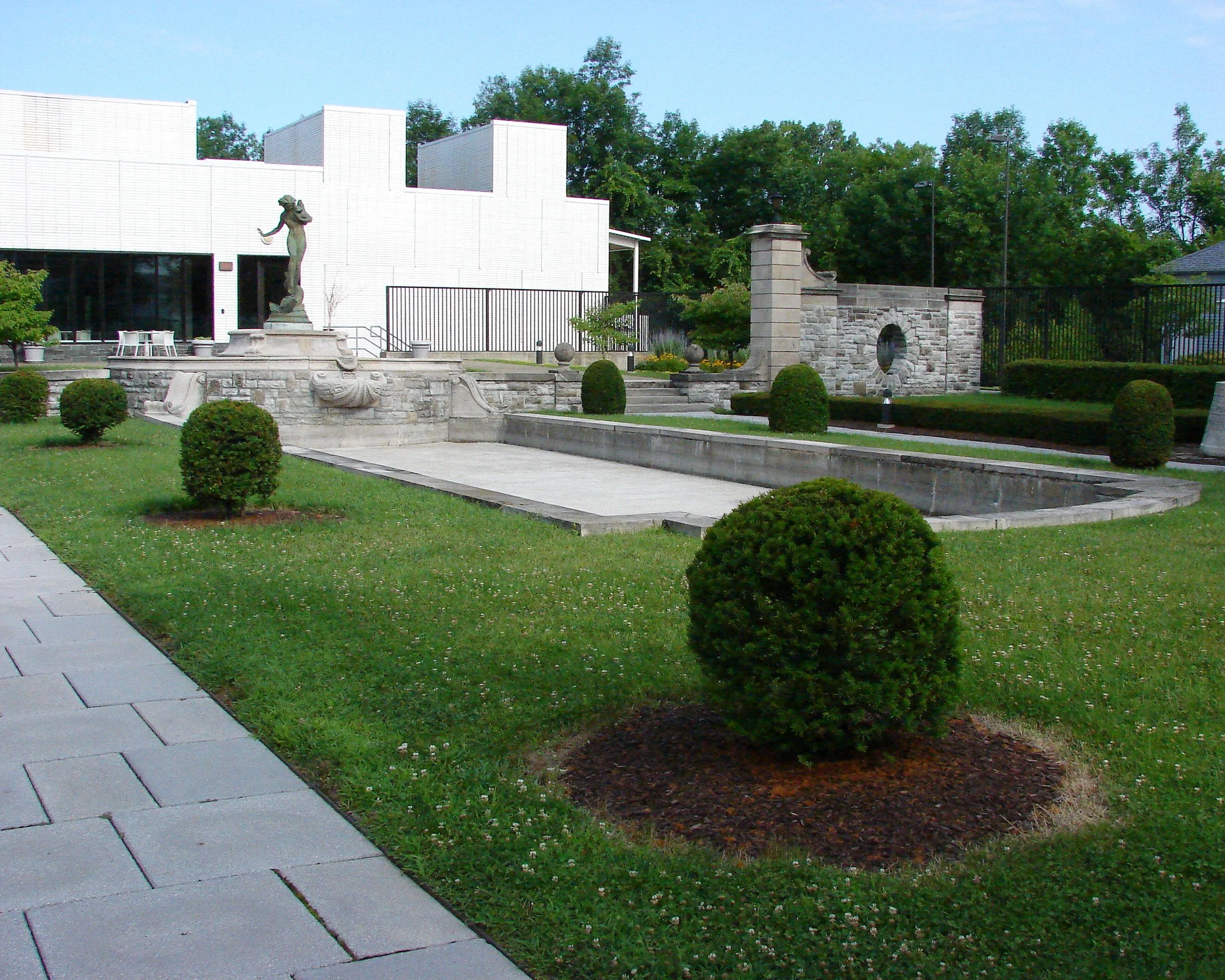 This is a photo of the Arkell Museum and Canajoharie Library Memorial Garden. It has an empty fountain, and in the background you can see Harriet Frishmuth's sculpture titled "Humoresque" towering over the pool.