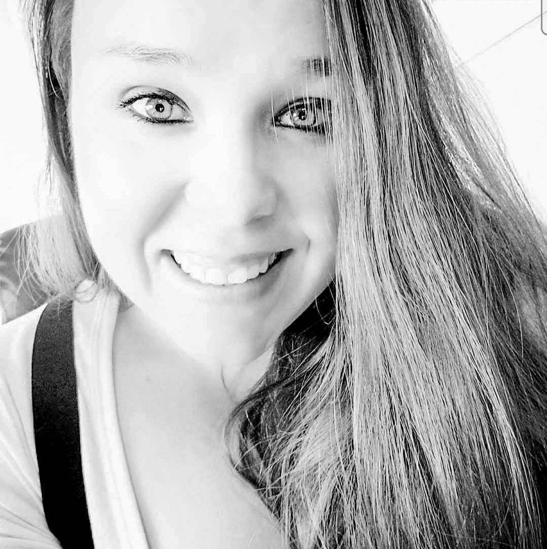 Black and white photo of a woman with long dark hair. She looks at the camera and is smiling.