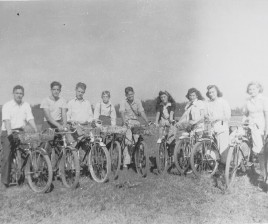 Black and white photo of a line of teenagers with bicycles.