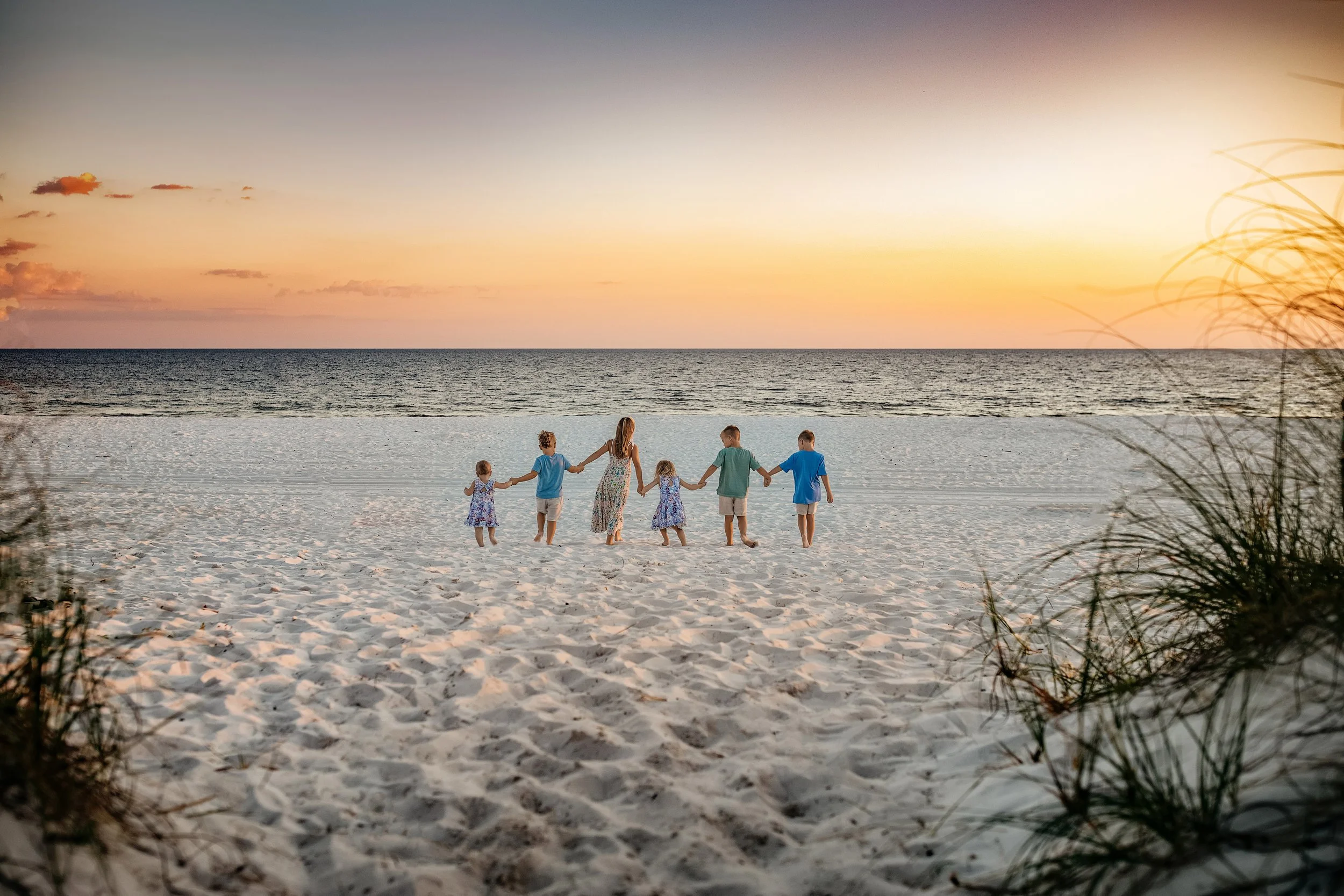 Cousins holding hands running on the sand during their sunset Rosemary Beach Family Beach Session