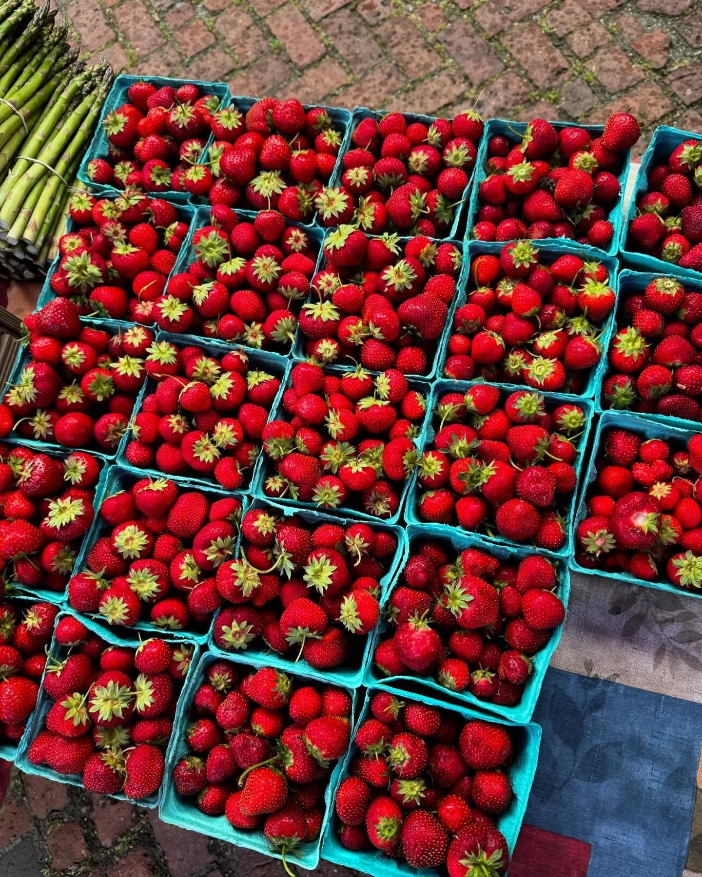 Fresh strawberries in blue baskets displayed on a table outdoors.