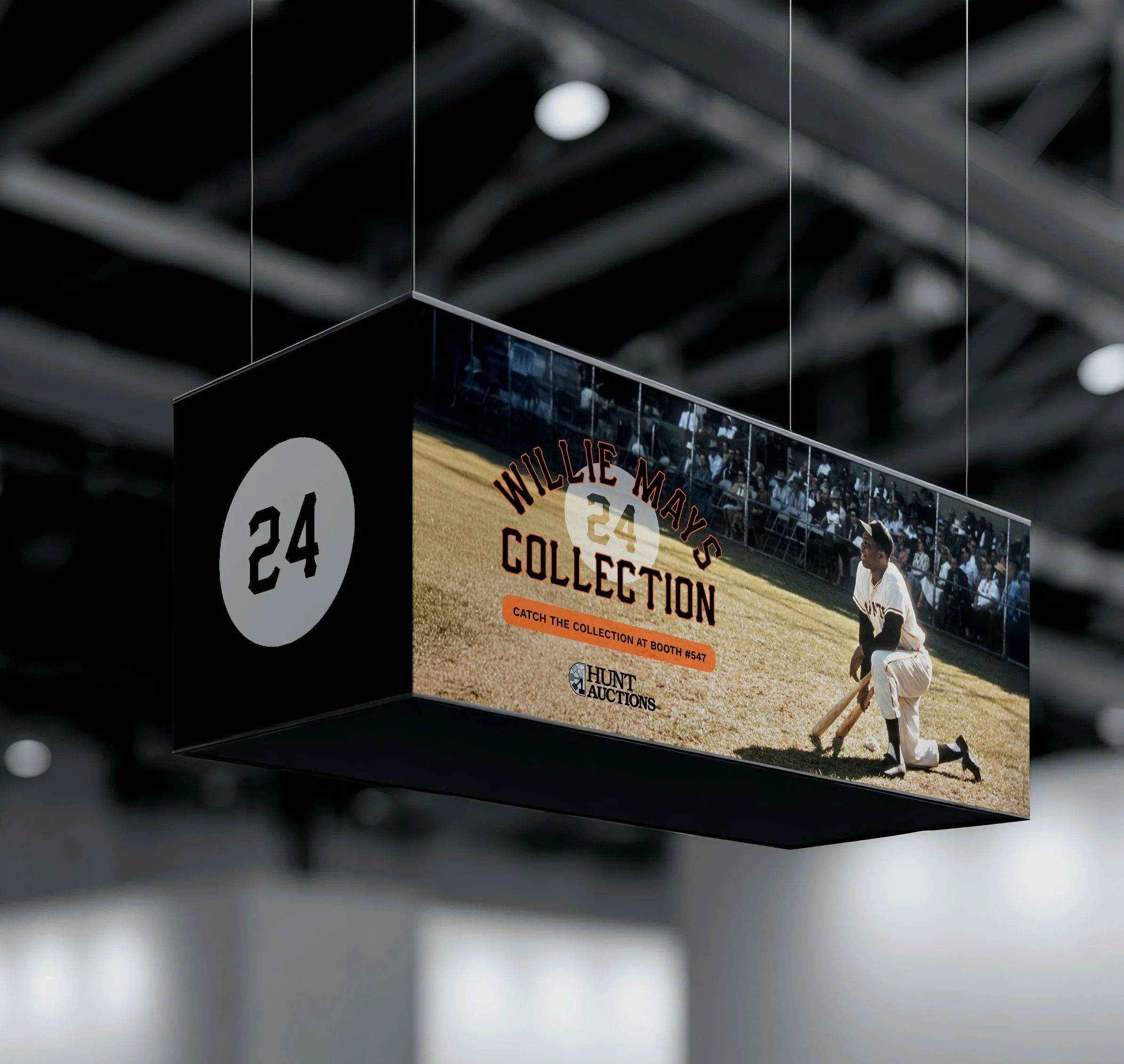 A hanging digital display promoting Willie Mays collection at Hunt Auctions, featuring a photo of Willie Mays in a baseball uniform on the field and the number 24.
