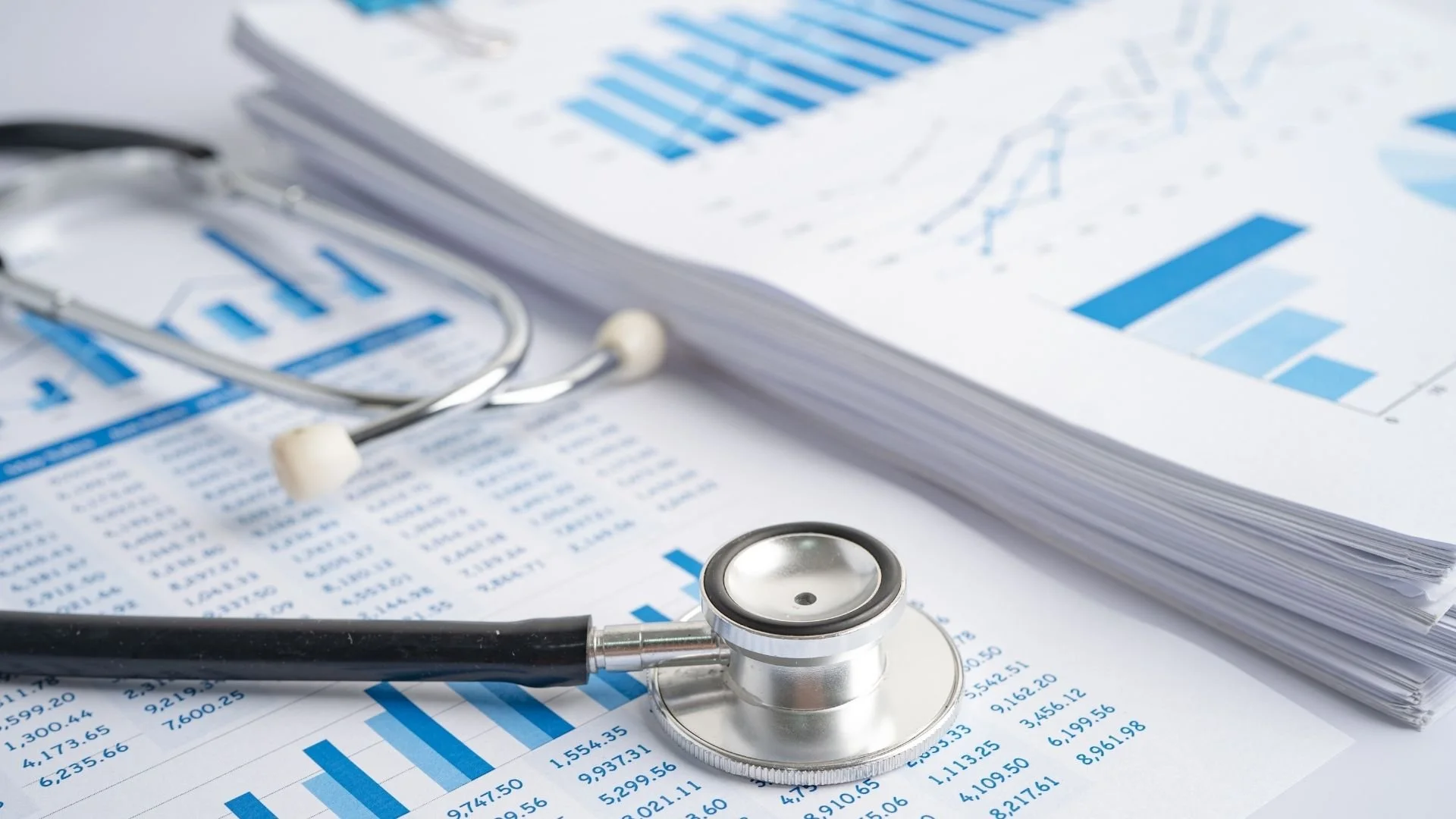 Medical paperwork with charts and graphs with a stethescope on top on the documents