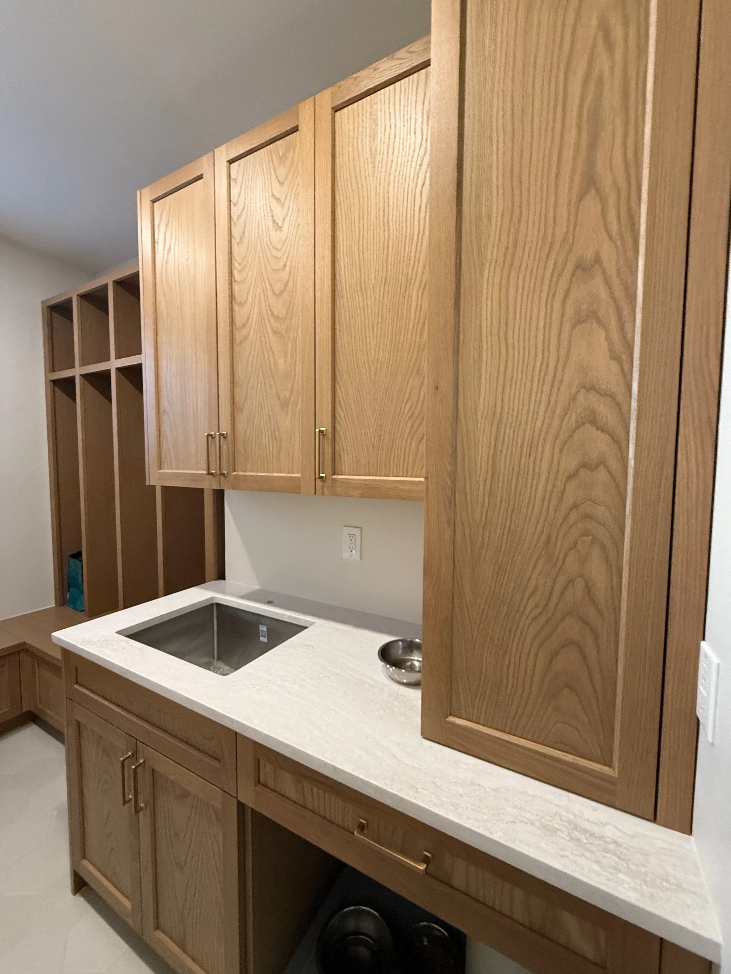 Kitchen with wooden cabinets, a white countertop, a built-in sink, and a small bowl, with open shelves on the left side.