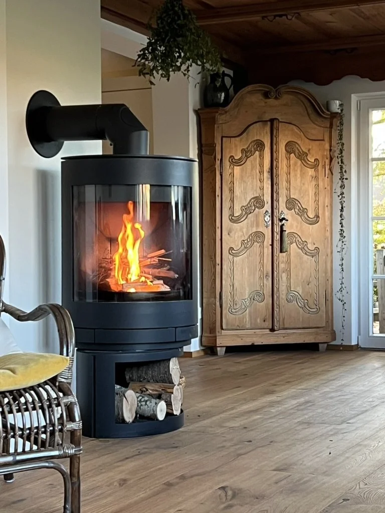 Moderner Holzofen mit brennendem Feuer in einem Wohnzimmer.