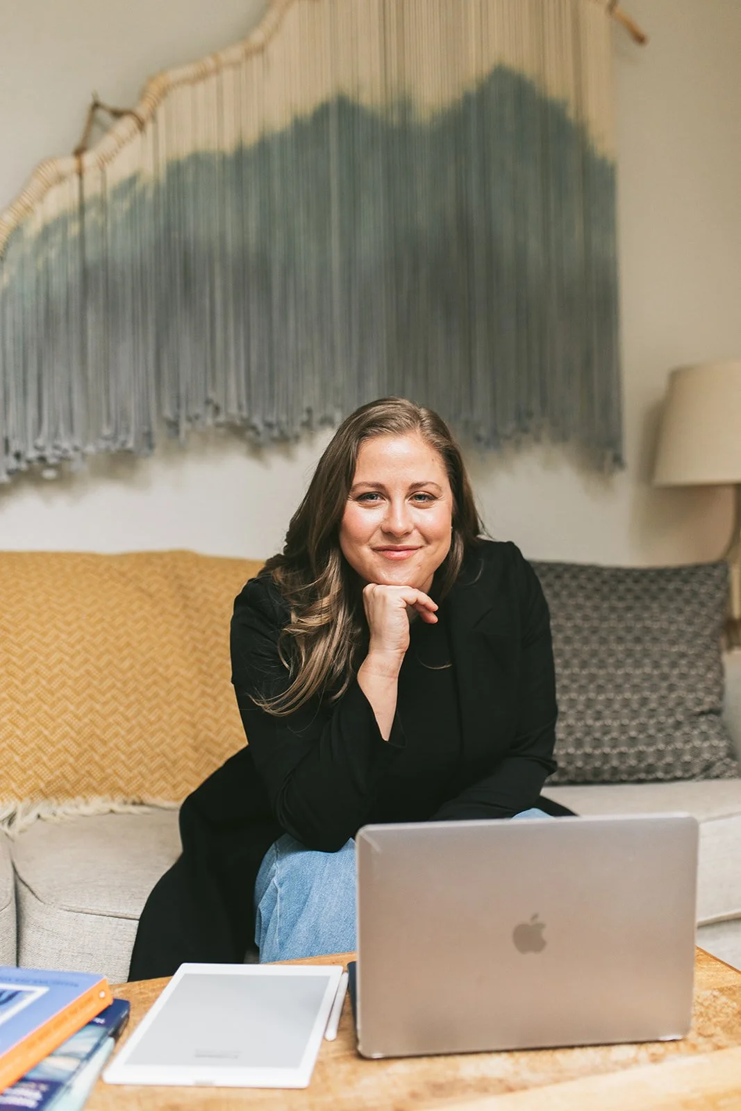 Meredith Garreau seated at her home office with a laptop, chin resting on her hand, smiling warmly at the camera