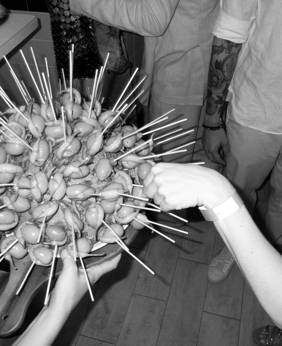 People are preparing appetizers with skewered stuffed olives at a gathering.