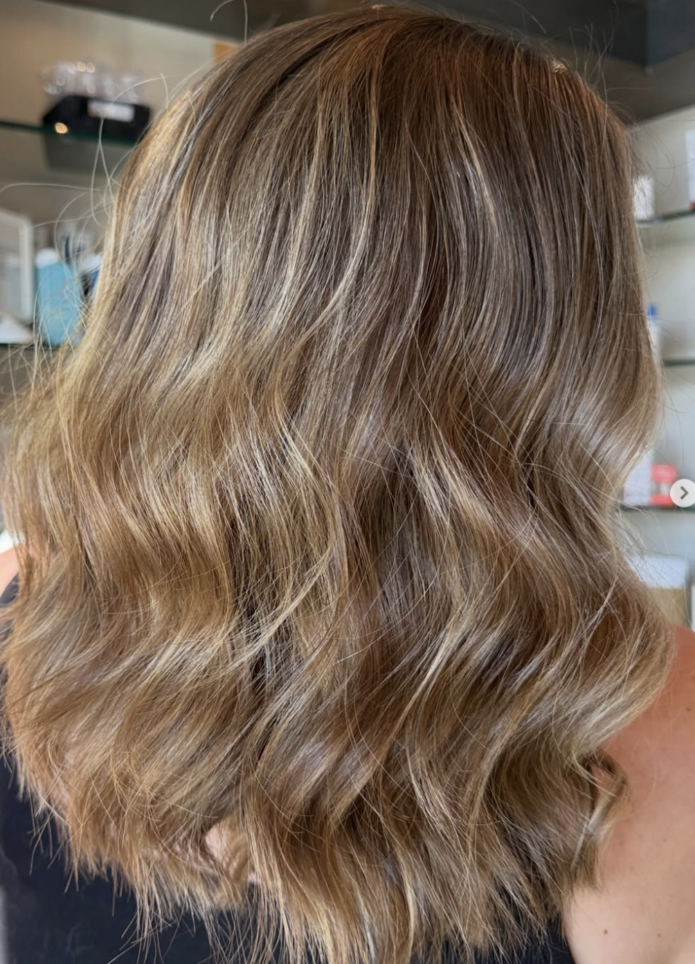 Close-up of wavy blonde hair with highlights, styled in loose waves.