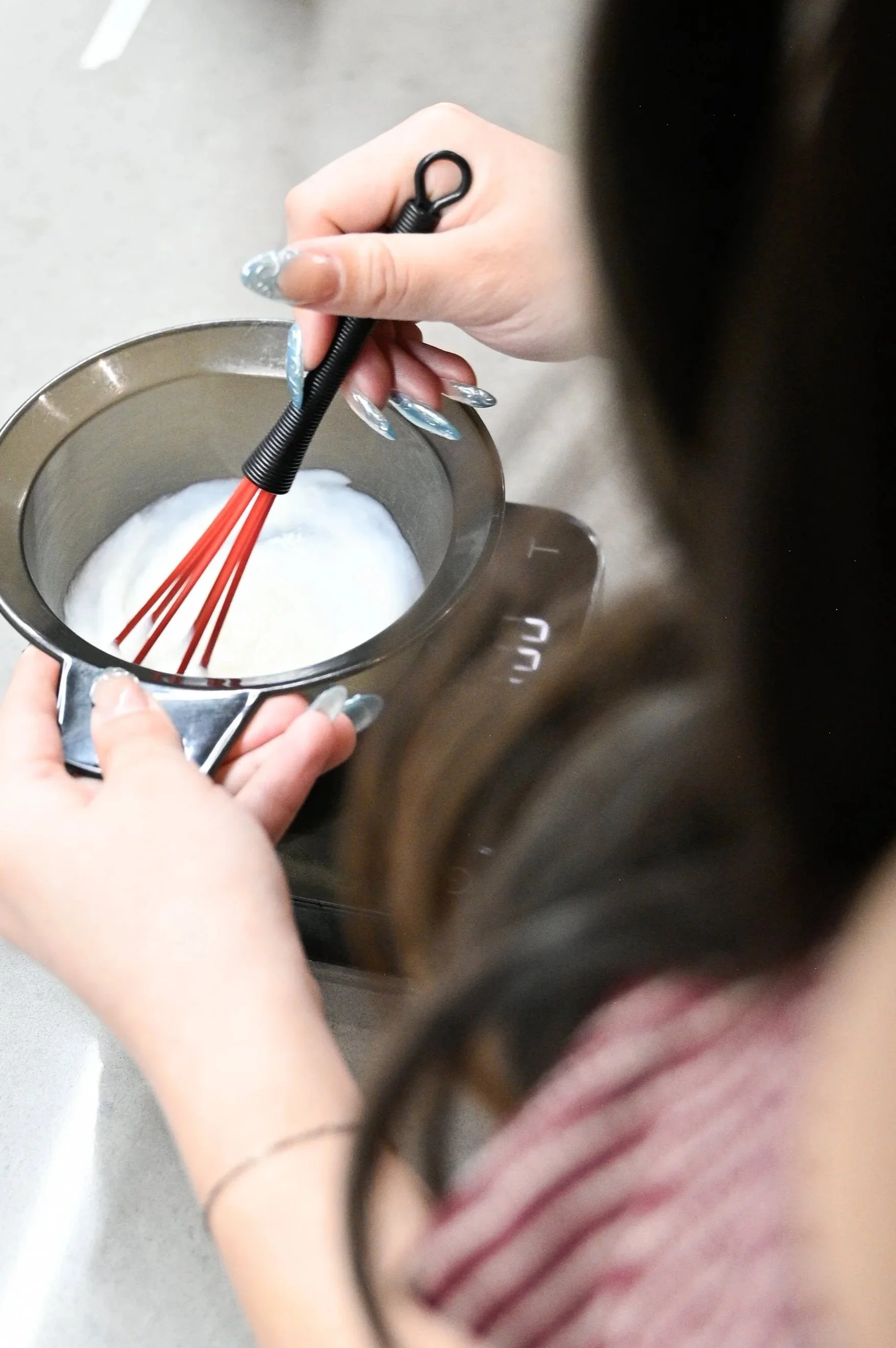 Person whisking ingredients in a mixing bowl on a kitchen counter.