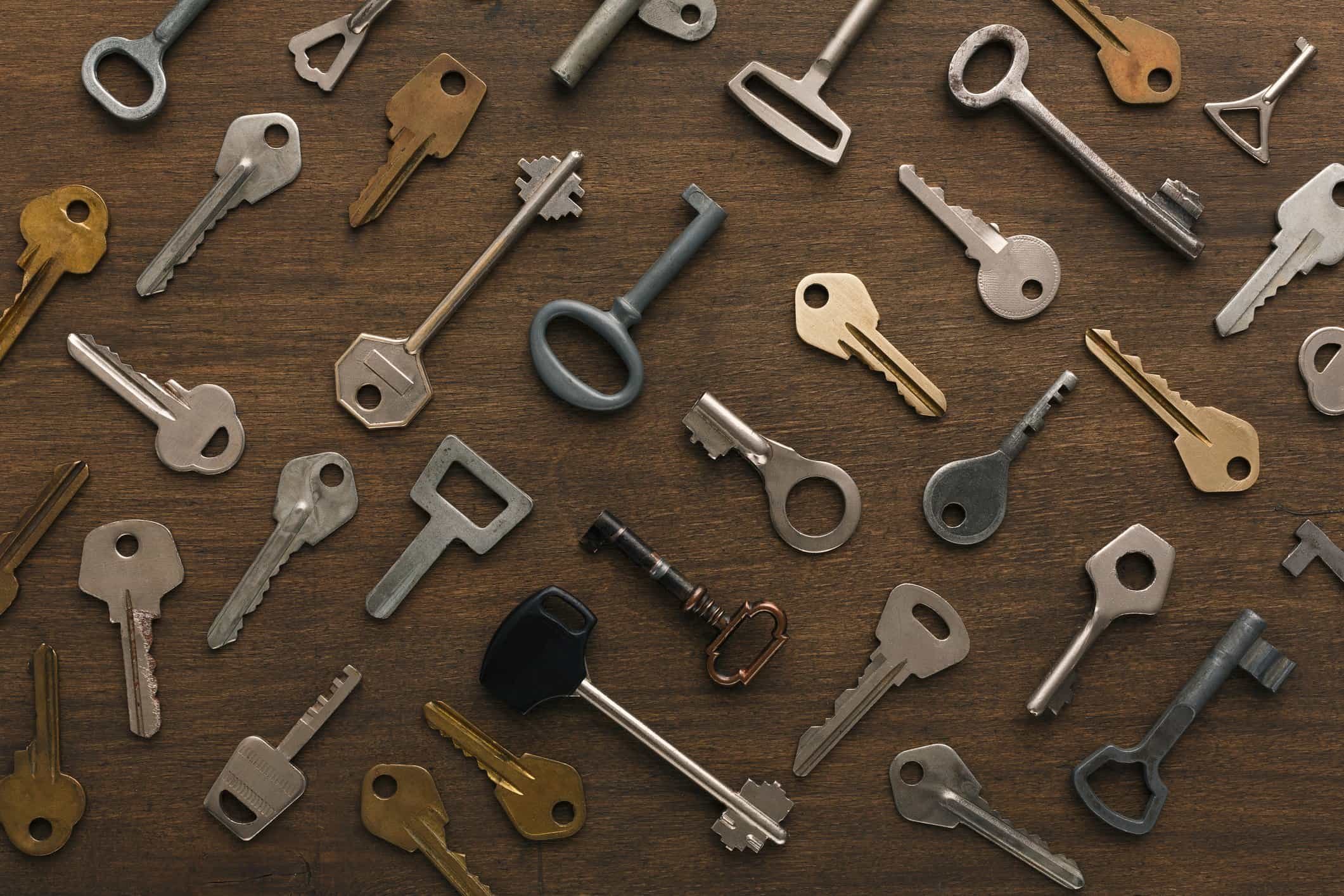 A collection of keys and key parts scattered on a wooden surface.