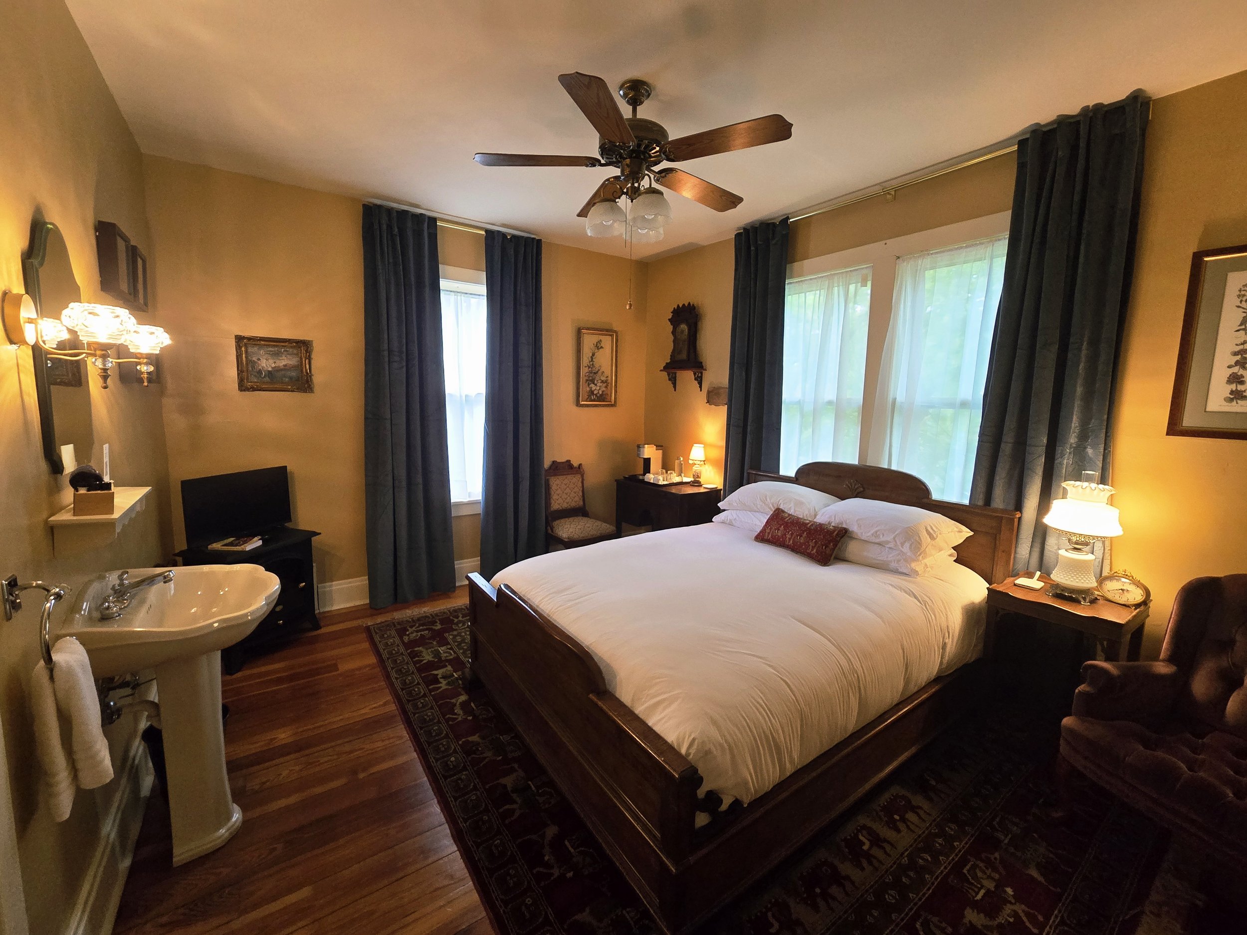 A cozy bedroom with queen size bed, ensuite bathroom and a ceiling fan.