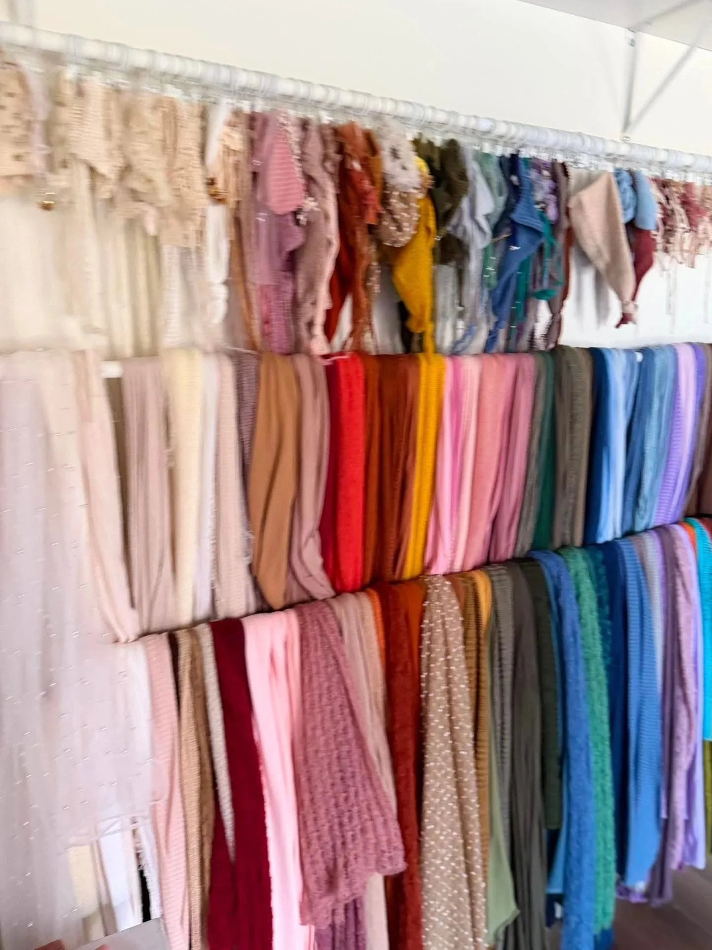 Display of colorful scarves hanging on a rack.