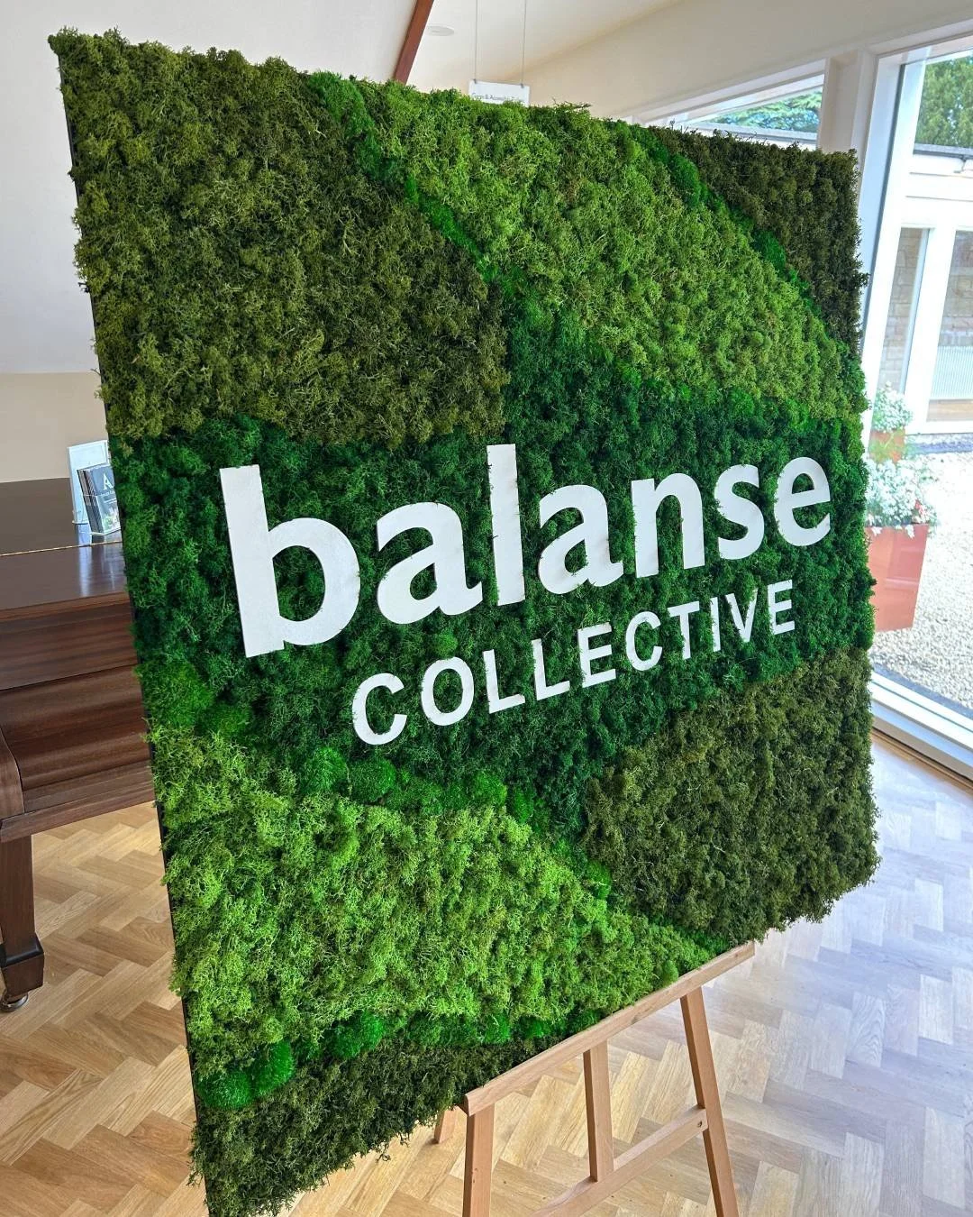 Large preserved moss business sign with white Balanse Collective lettering.