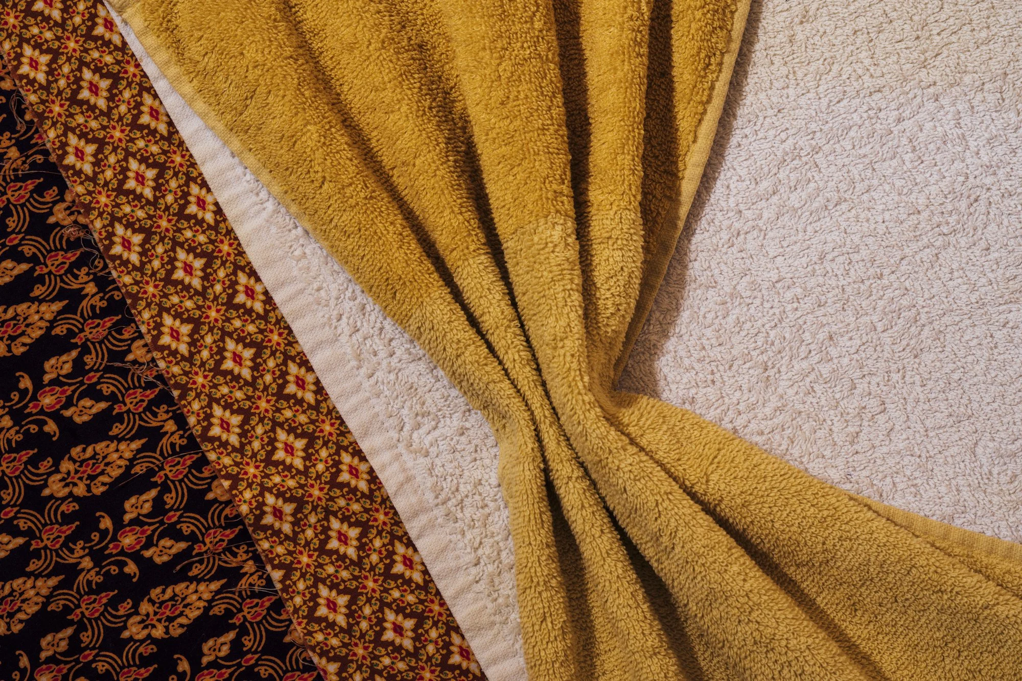 A collection of colorful blankets and towels, displaying various patterns including floral designs and textured fabrics, arranged on a surface.