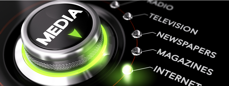 A close-up of a media dial with options like radio, television, newspapers, magazines, internet, and a central button labeled 'MEDIA' in white text.