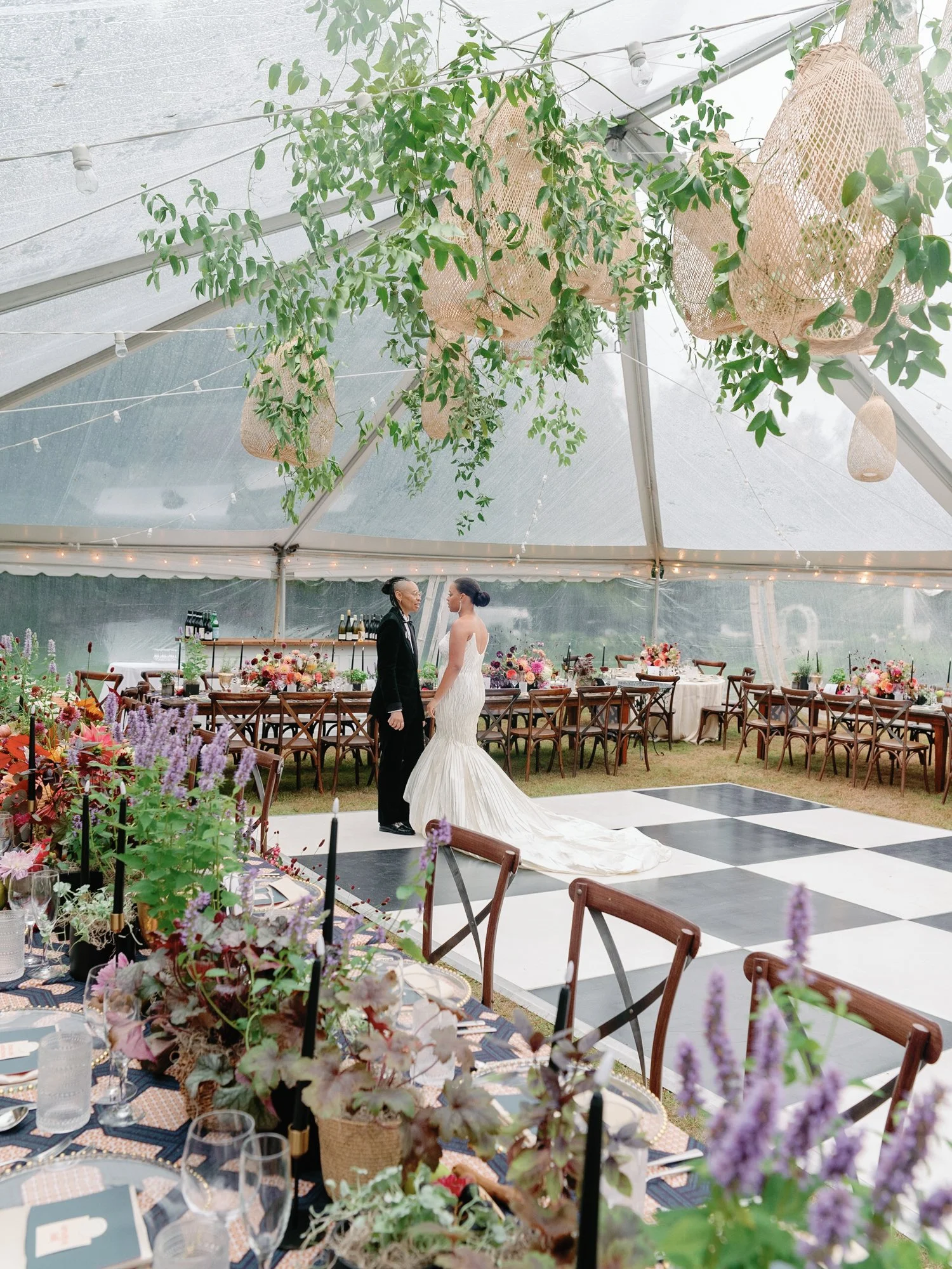 Couple at wedding ceremony inside a decorated tent with hanging greenery and woven hanging lights at Lambert's Cove Inn on Martha's Vineyard.