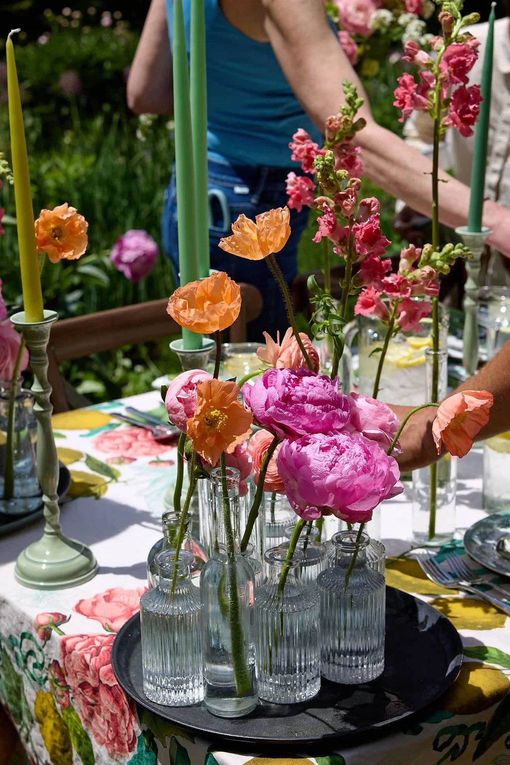 Vase arrangement with pink and peach poppies on a floral tablecloth at an outdoor wedding reception at Lambert's Cove Inn on Martha's Vineyard.
