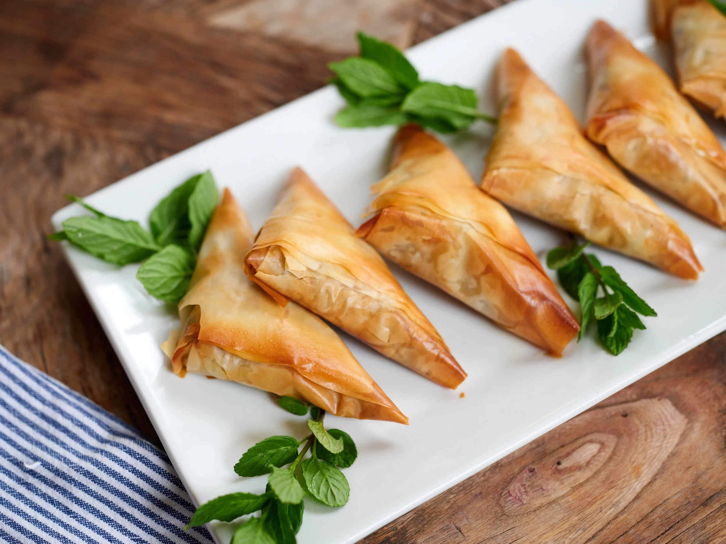 Four crispy pastries on a white rectangular plate garnished with fresh mint leaves at Restaurant Foster at Lambert's Cove Inn on Martha's Vineyard.