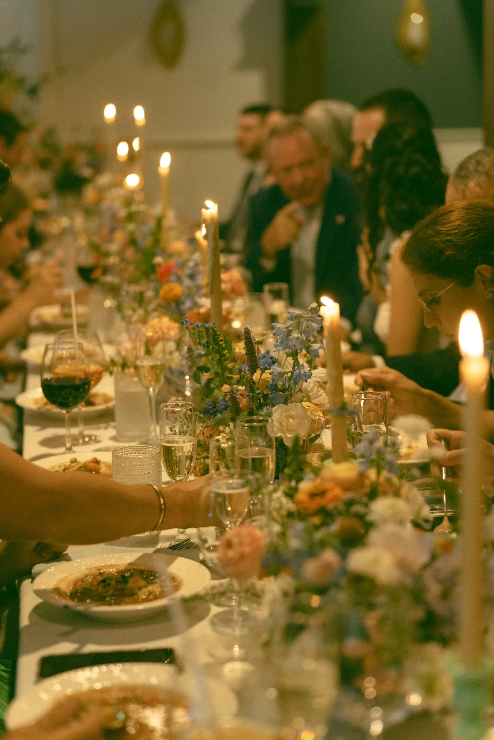 A formal wedding reception at Lambert's Cove Inn on Martha's Vineyard with people seated at a long table decorated with flowers and candles.