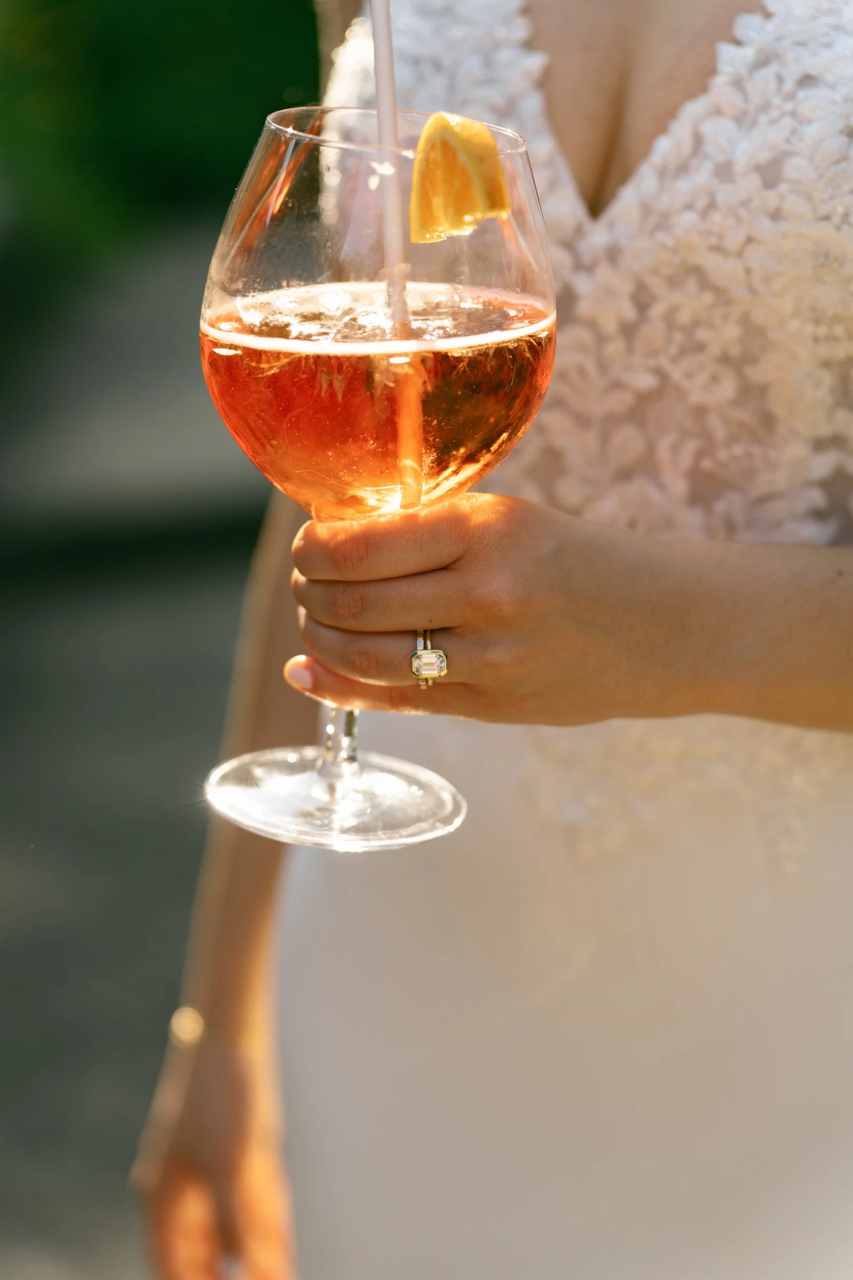 Woman holding a glass of pinkish-orange drink with a lemon wedge garnish at Lambert's Cove Inn on Martha's Vineyard.