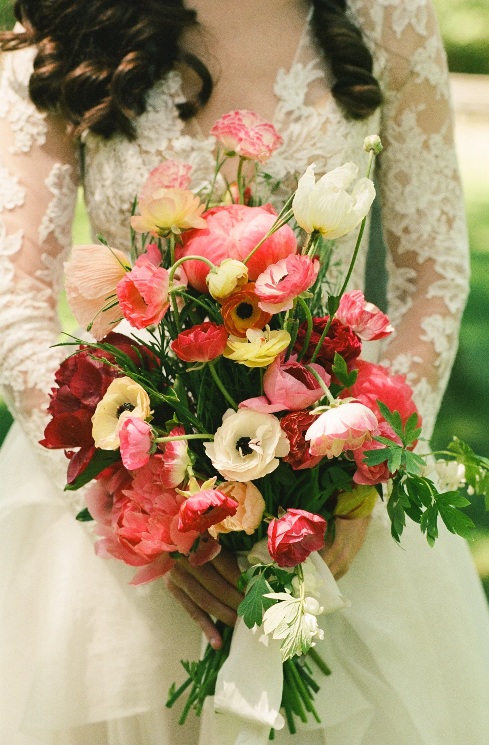 A person holding a colorful bouquet of flowers, with a lace dress visible during a wedding at Lambert's Cove Inn on Martha's Vineyard.