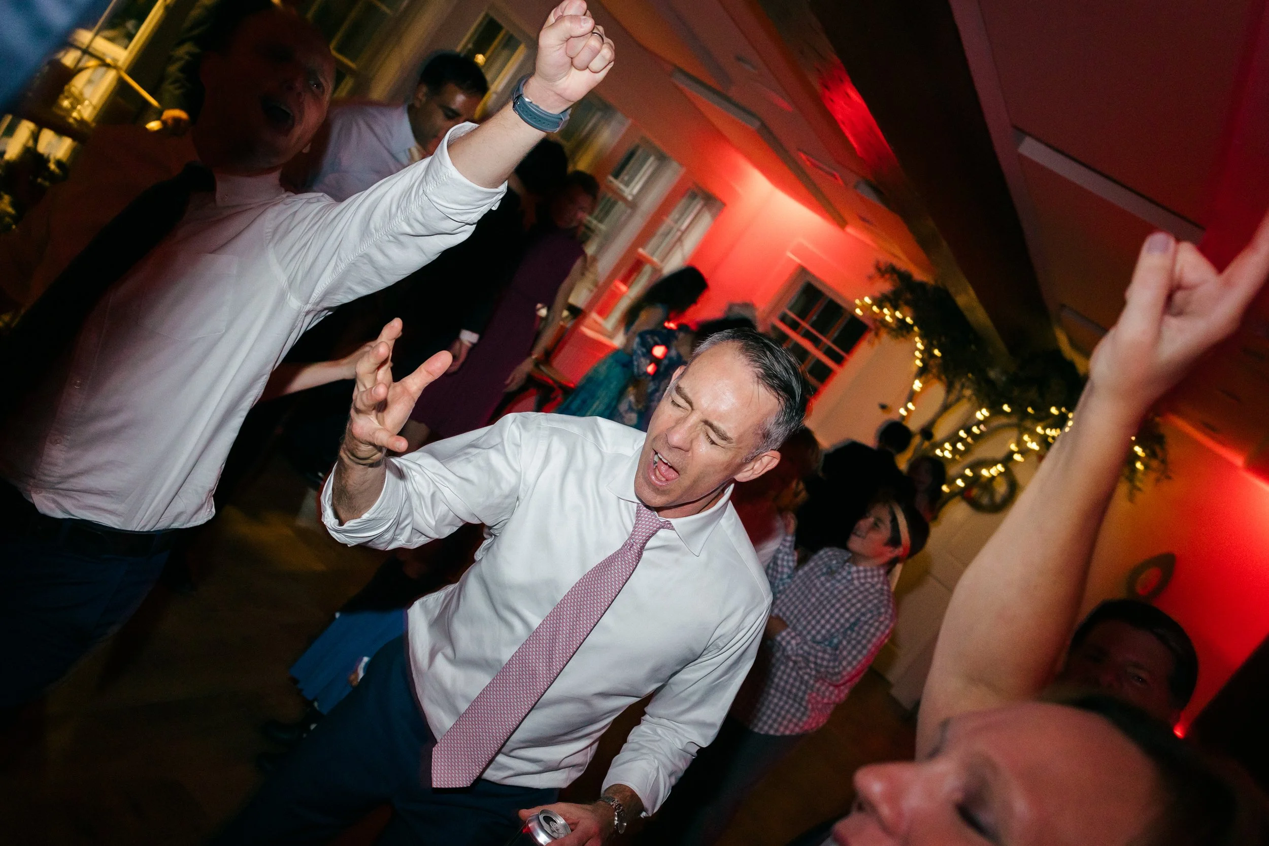 People dancing indoors at wedding reception at Lambert's Cove Inn on Martha's Vineyard, with festive lighting and decorations.