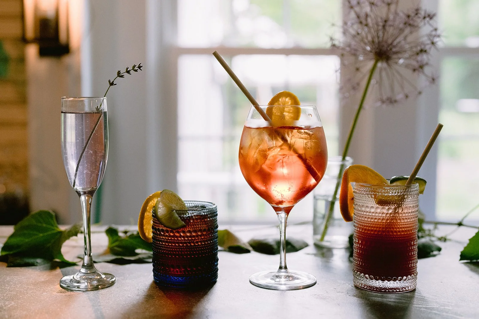 Various colorful cocktails and beverages on a table with flowers and leaves in the background at Restaurant Foster and Mermaid Bar on Martha's Vineyard.