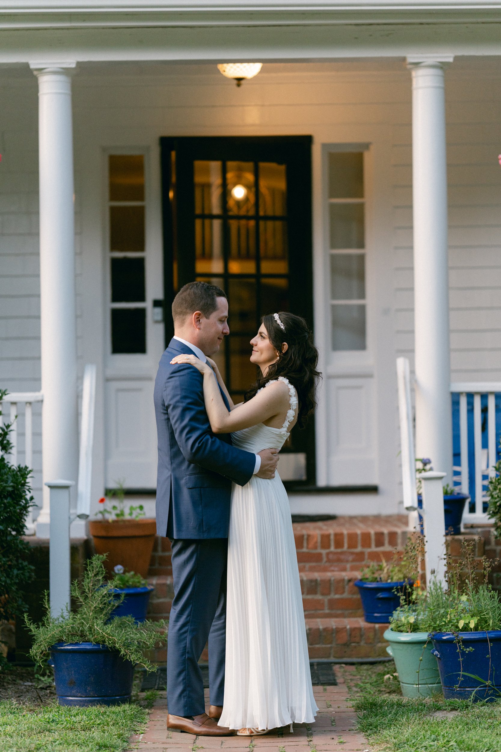 A bride and groom standing face to face on a small brick walkway in front of at Lambert's Cove Inn on Martha's Vineyard, sharing a moment of intimacy during their wedding day in West Tisbury.
