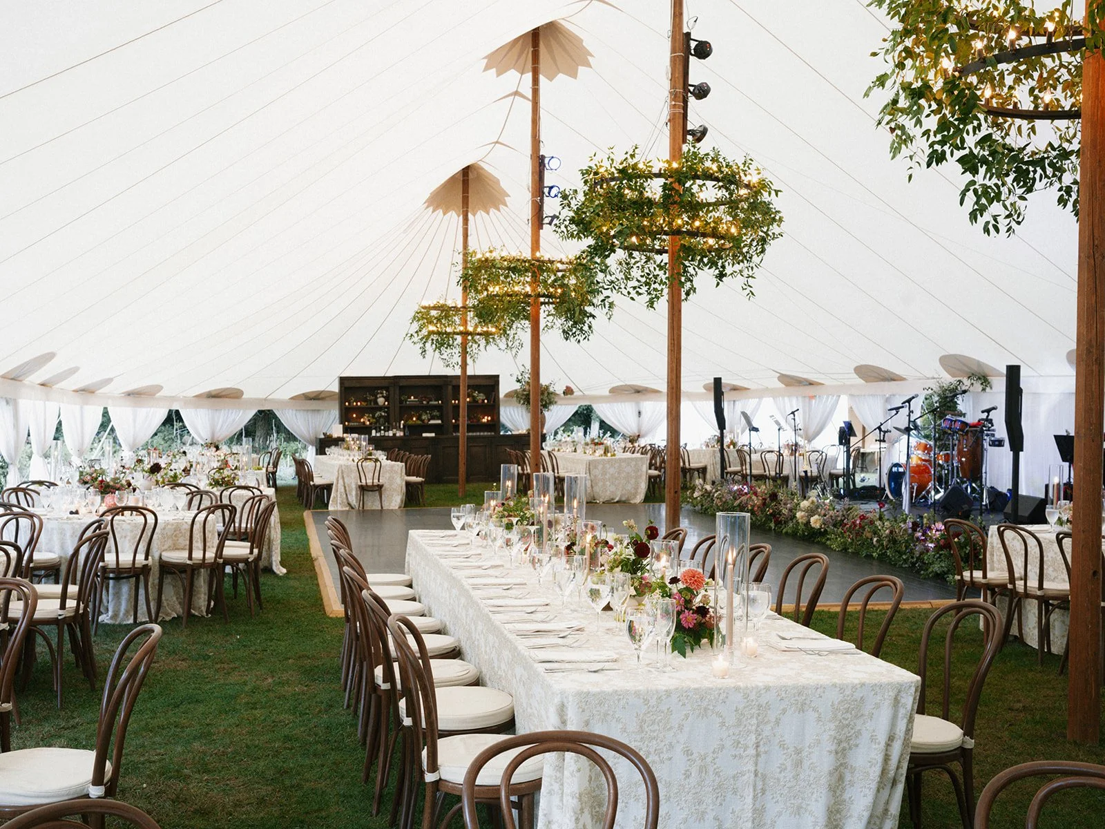 Elegant wedding reception inside a large white tent with decorated tables, floral arrangements, and musical instruments on stage, ready for a wedding reception at Lambert's Cove Inn on Martha's Vineyard.