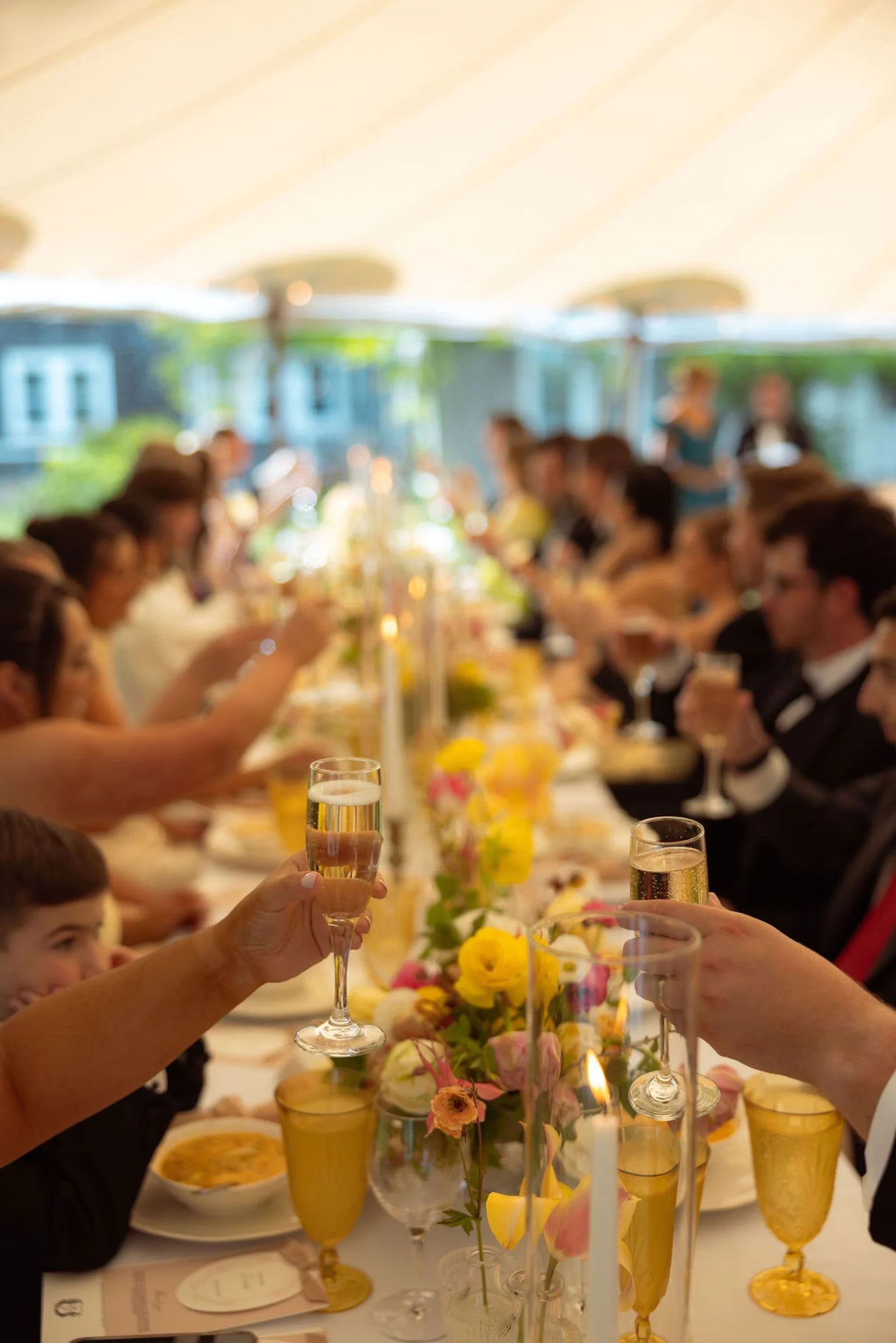 A wedding celebration at Lambert's Cove Inn on Martha's Vineyard where people are toasting with glasses of champagne at a decorated dinner table.