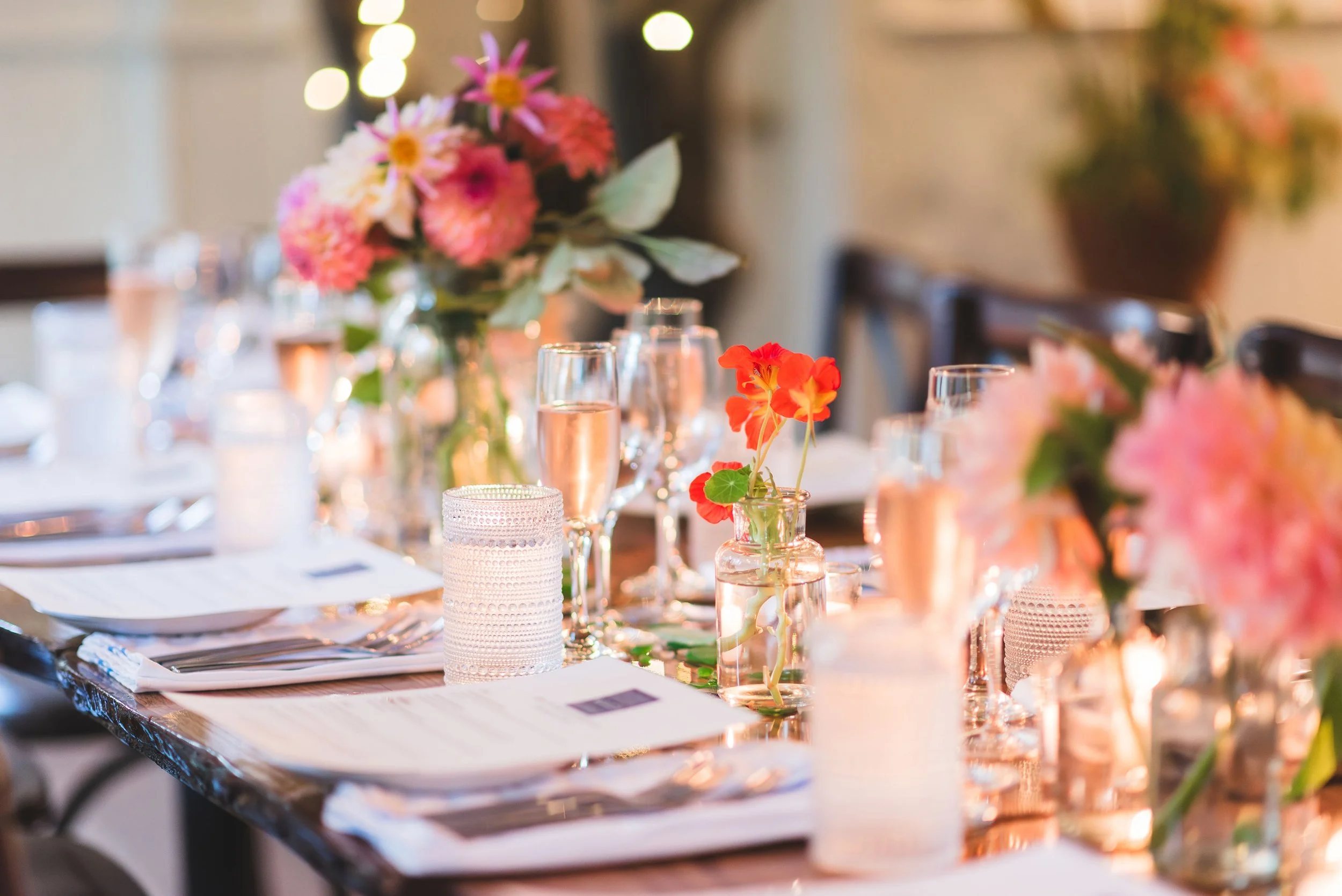 Elegant table setup with floral centerpieces, candles, wine glasses, and place settings for a wedding reception at Lambert's Cove Inn on Martha's Vineyard.