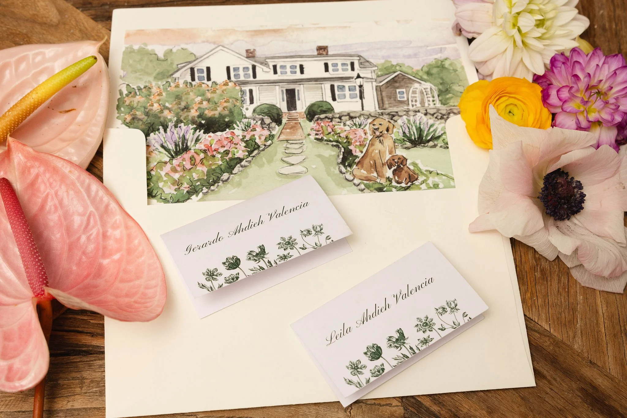 Colorful watercolor painting of a house with a garden, surrounded by flowers, with a dog and a puppy sitting on the grass in front.