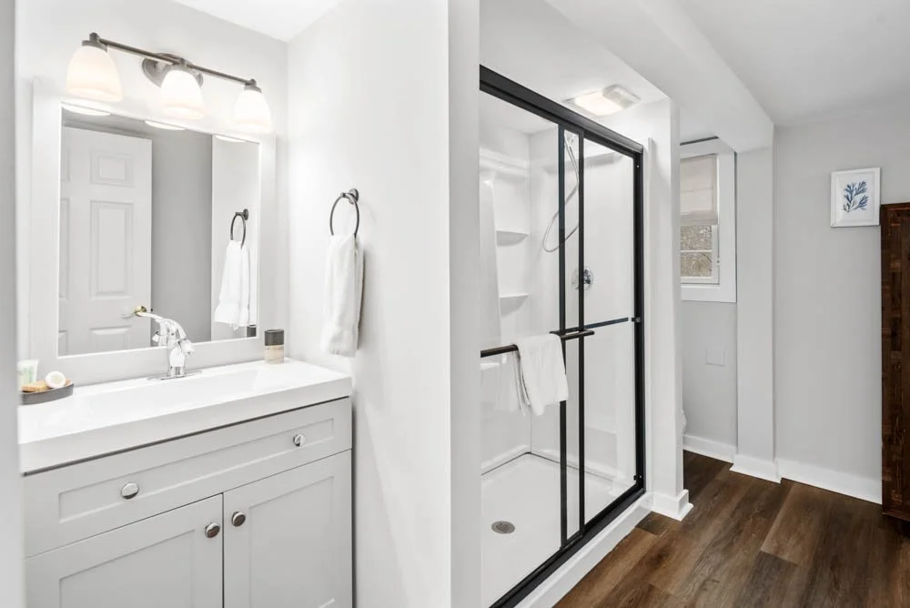 Bathroom with vanity, mirror, towels, and a glass shower enclosure with a towel hanging on the handle