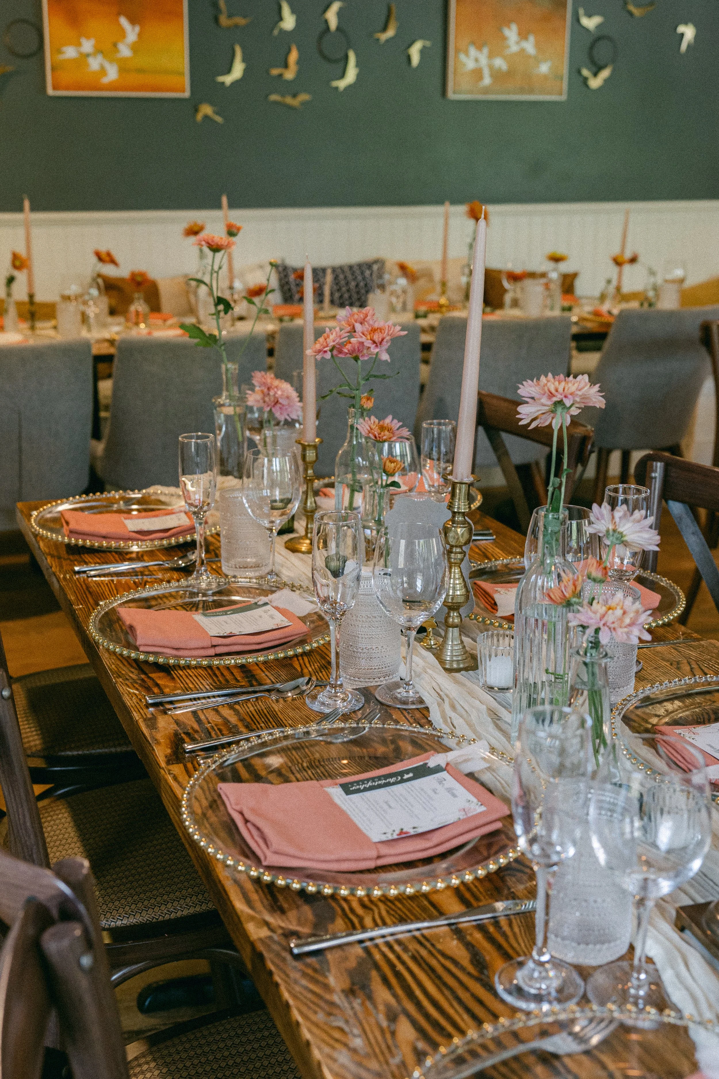 A decorated dining table set with pink linens, glassware, candles, and pink flowers in vases, ready for wedding reception at Lambert's Cove Inn on Martha's Vineyard.