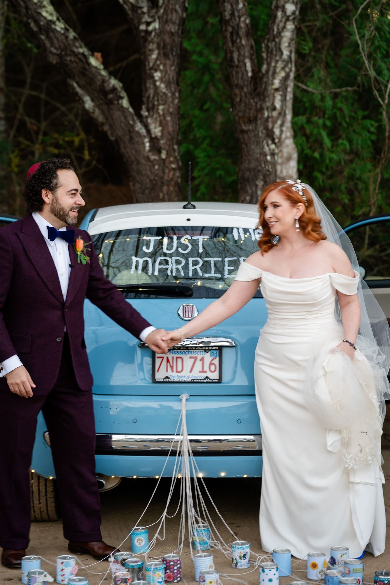 A bride and groom holding hands in front of a blue car at Lambert's Cove Inn on Martha's Vineyard.