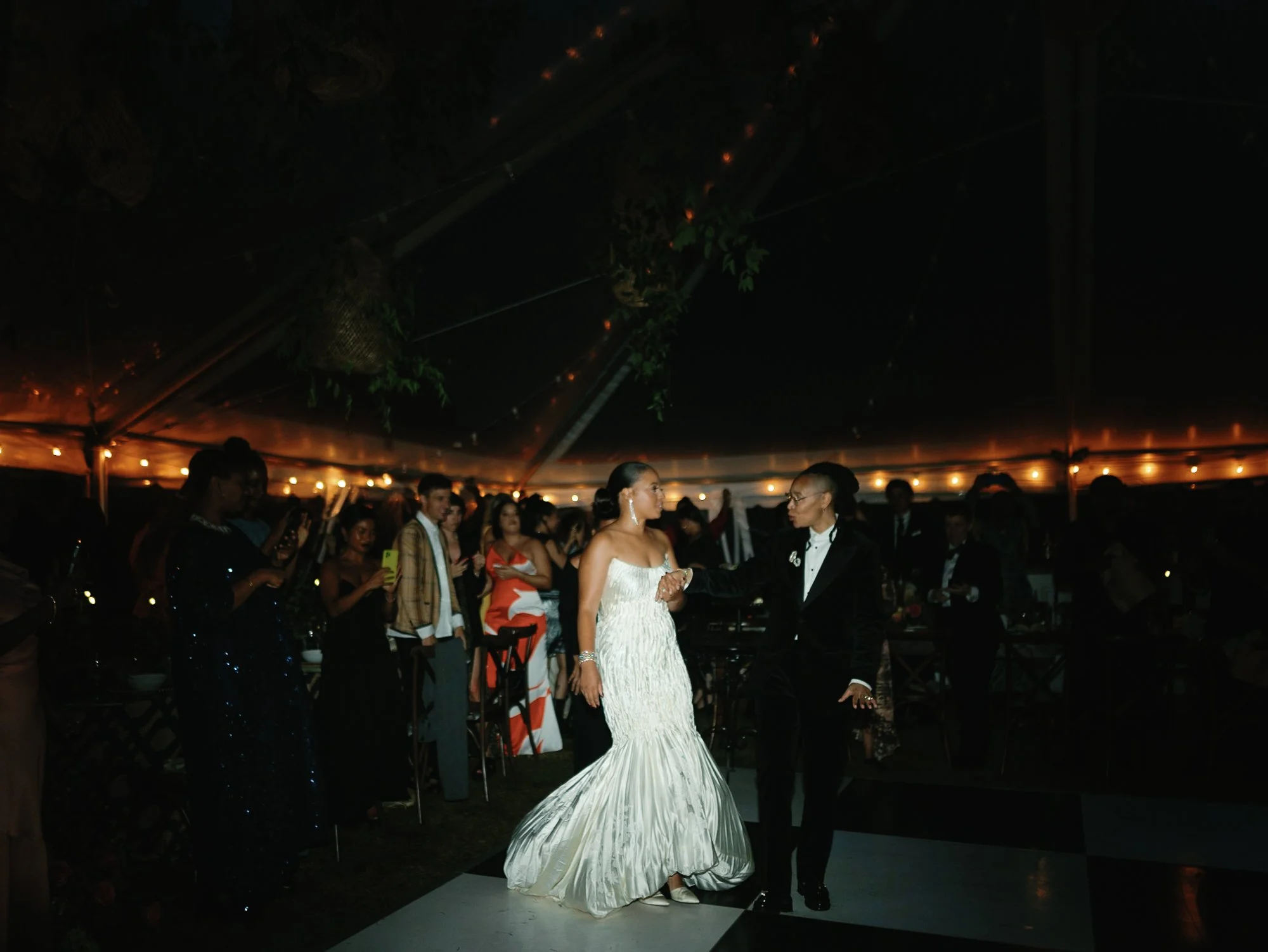 A bride in a white wedding gown dancing with a man in a black tuxedo during a wedding reception at night at Lambert's Cove Inn on Martha's Vineyard in West Tisbury, Massachusetts, one of the top wedding venues on the island. 