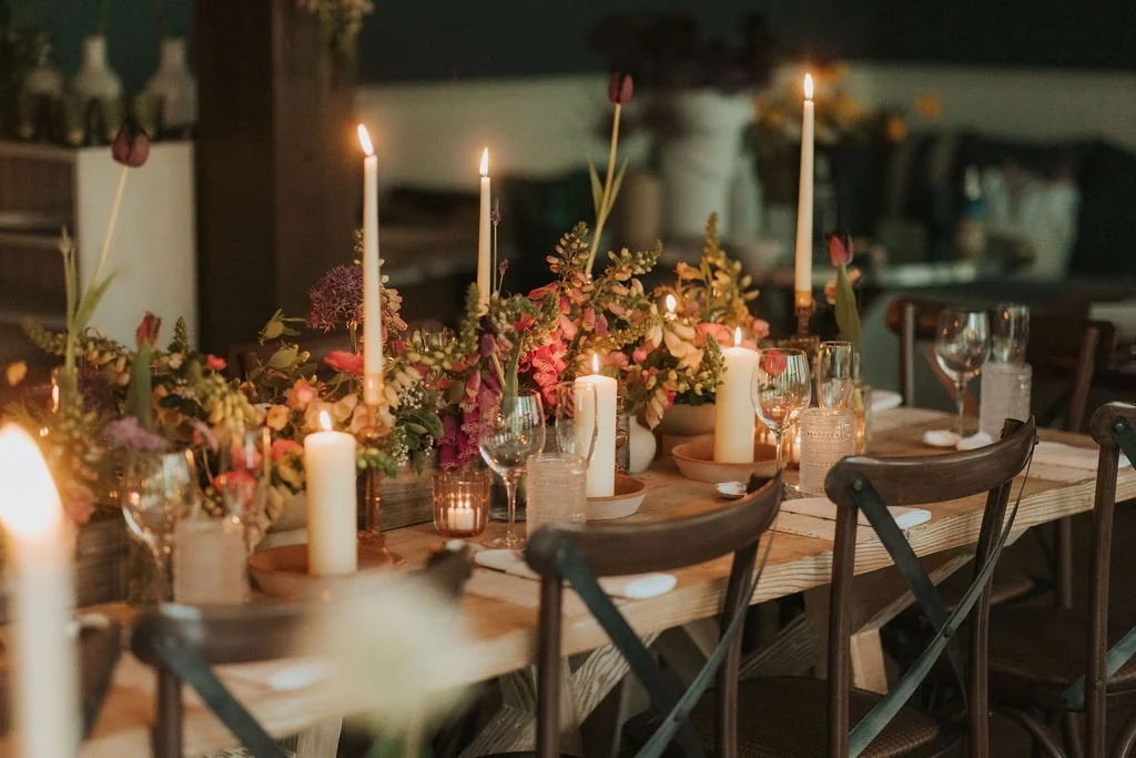 Dinner table decorated with candles, flowers, and tableware for a celebration or gathering.