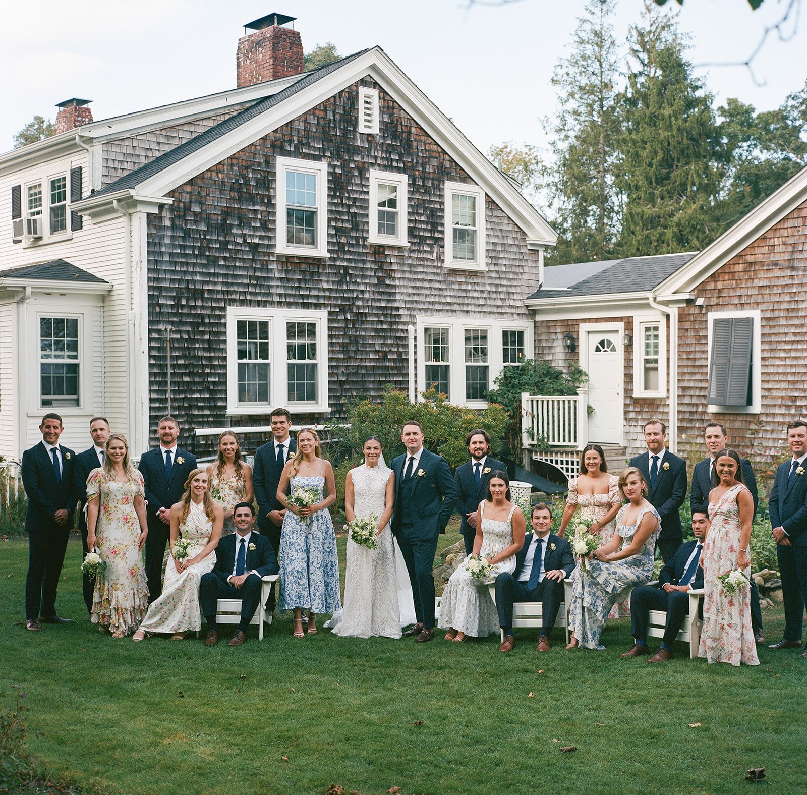 Group of people in wedding attire posing outdoors in front of Lambert's Cove Inn on Martha's Vineyard.