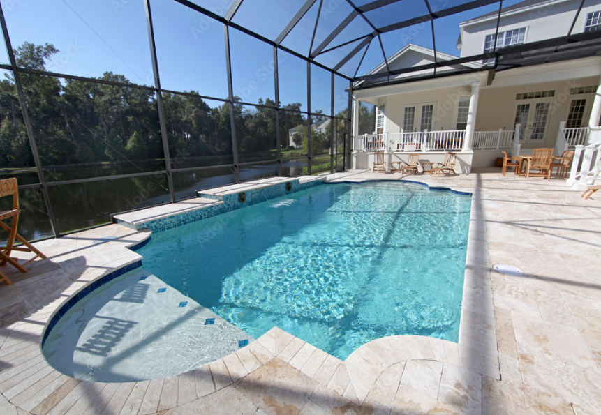 Enclosed backyard pool area with a blue swimming pool, white patio tiles, outdoor chairs, and a white house in the background.